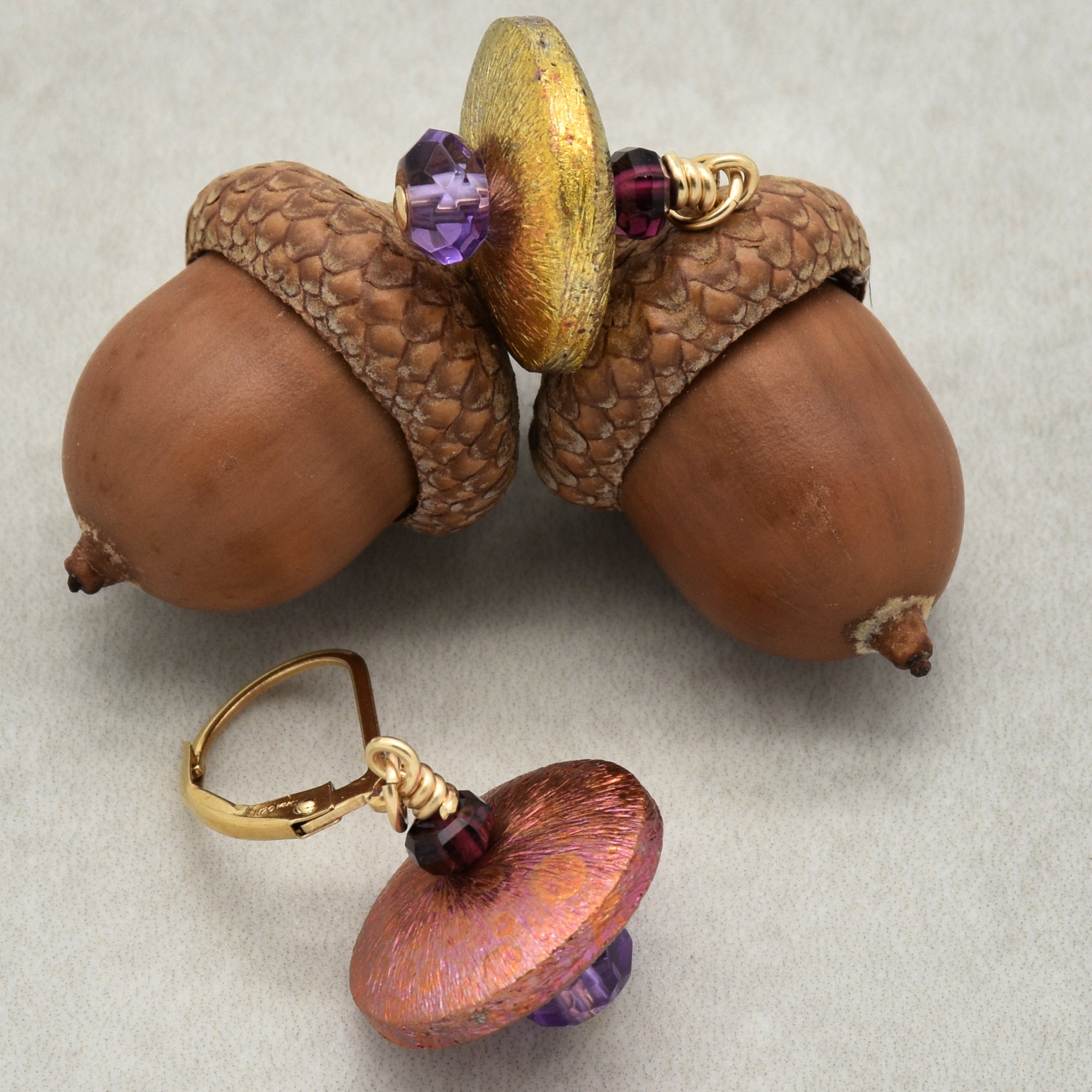 The image shows a pair of earrings. The earrings are designed with a couple of colorful beads and have a metal clasp for attachment. The clasp mechanism and size indicate that these are meant to be worn on the ears.