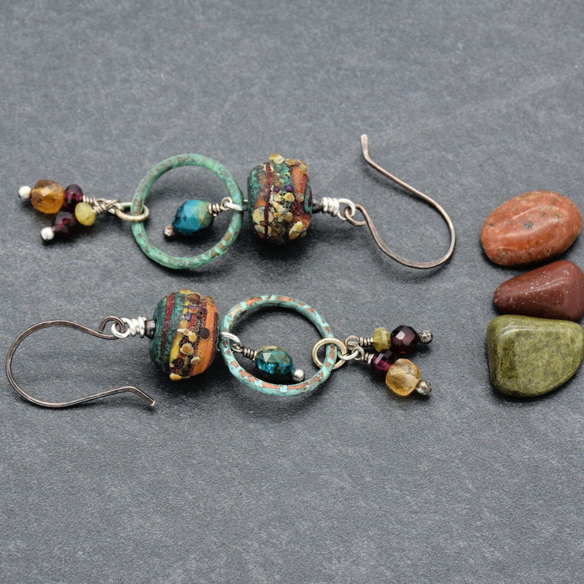 The image shows a pair of earrings. They have hooks for pierced ears and feature decorative beads and small dangling elements.