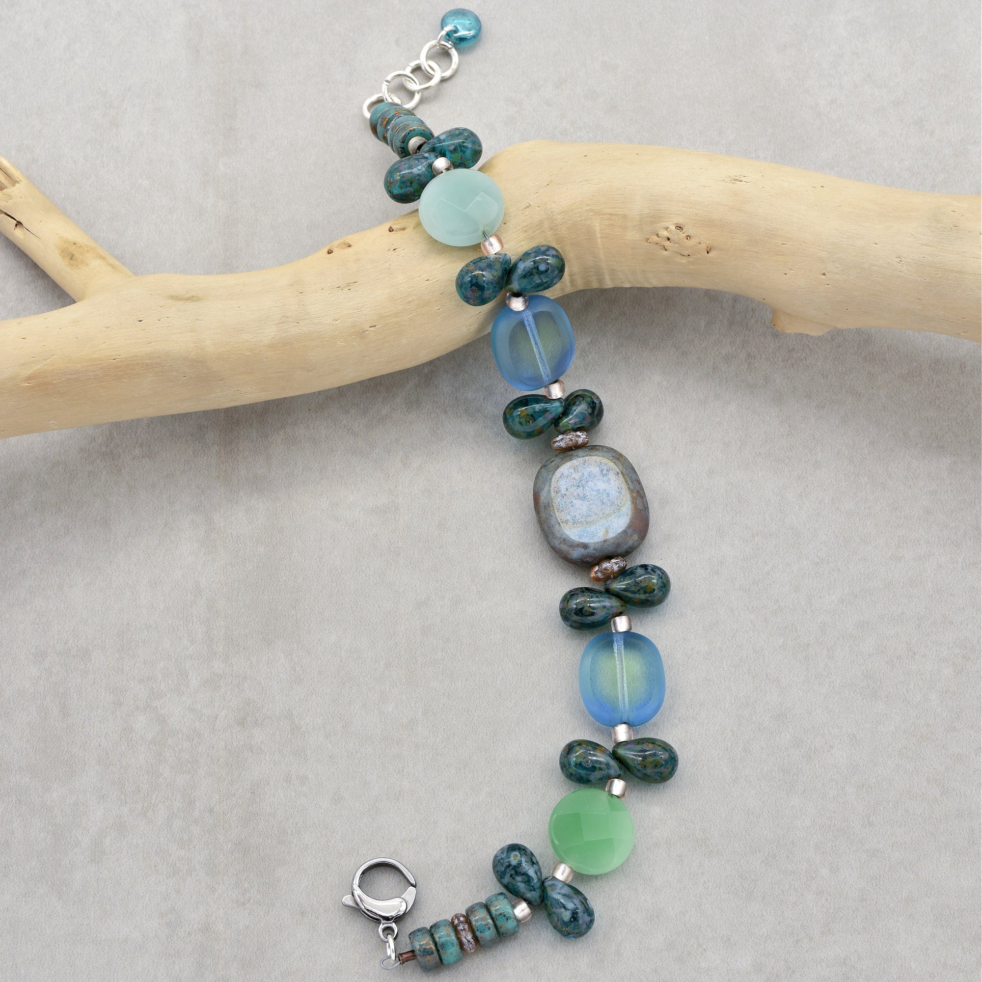 This image shows a bracelet. The length and clasp style are characteristic of a bracelet rather than a necklace or earring. The piece features various beads in shades of blue and green strung together.
