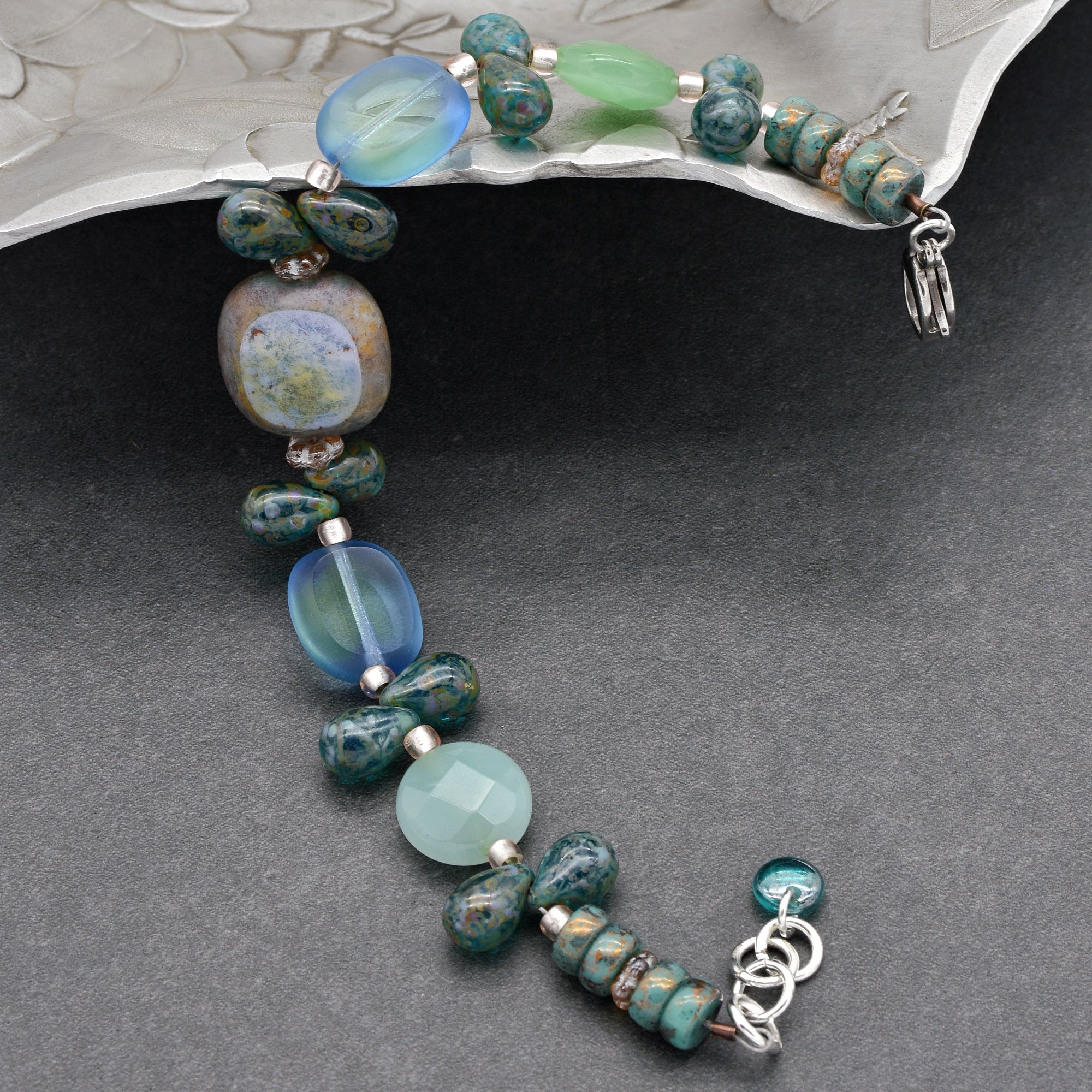 This image shows a bracelet. The jewelry is relatively short and has a clasp, which is characteristic of a bracelet rather than a necklace or an earring. The beads are varied in color and shape, giving it an artisanal look.