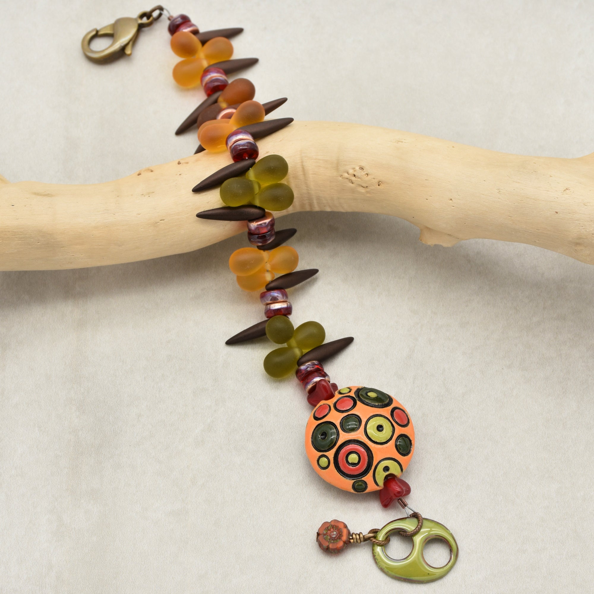 This image shows a bracelet. It features a clasp for securing it around the wrist, along with colorful beads and decorative elements. The design and length are consistent with what you would expect in a bracelet.