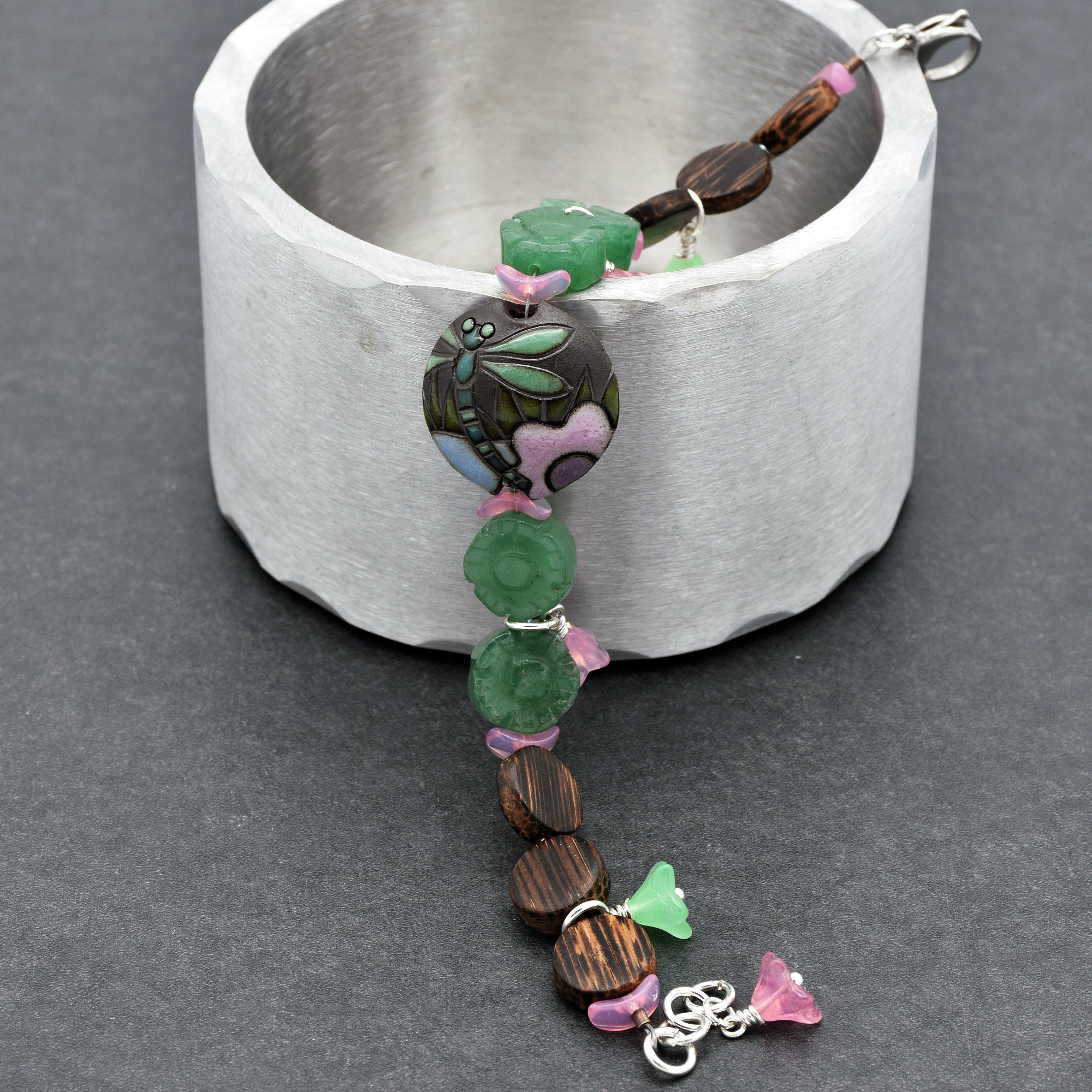 This image shows a bracelet. You can tell because of the small circumference and the presence of a clasp that is typical for bracelets. The design also includes beads and a central decorative piece with a dragonfly motif.