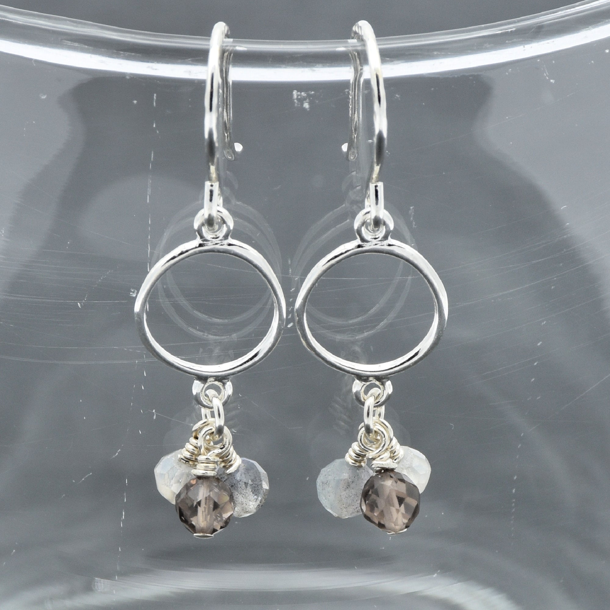 Silver earrings with circular designs and small beads on a clear background