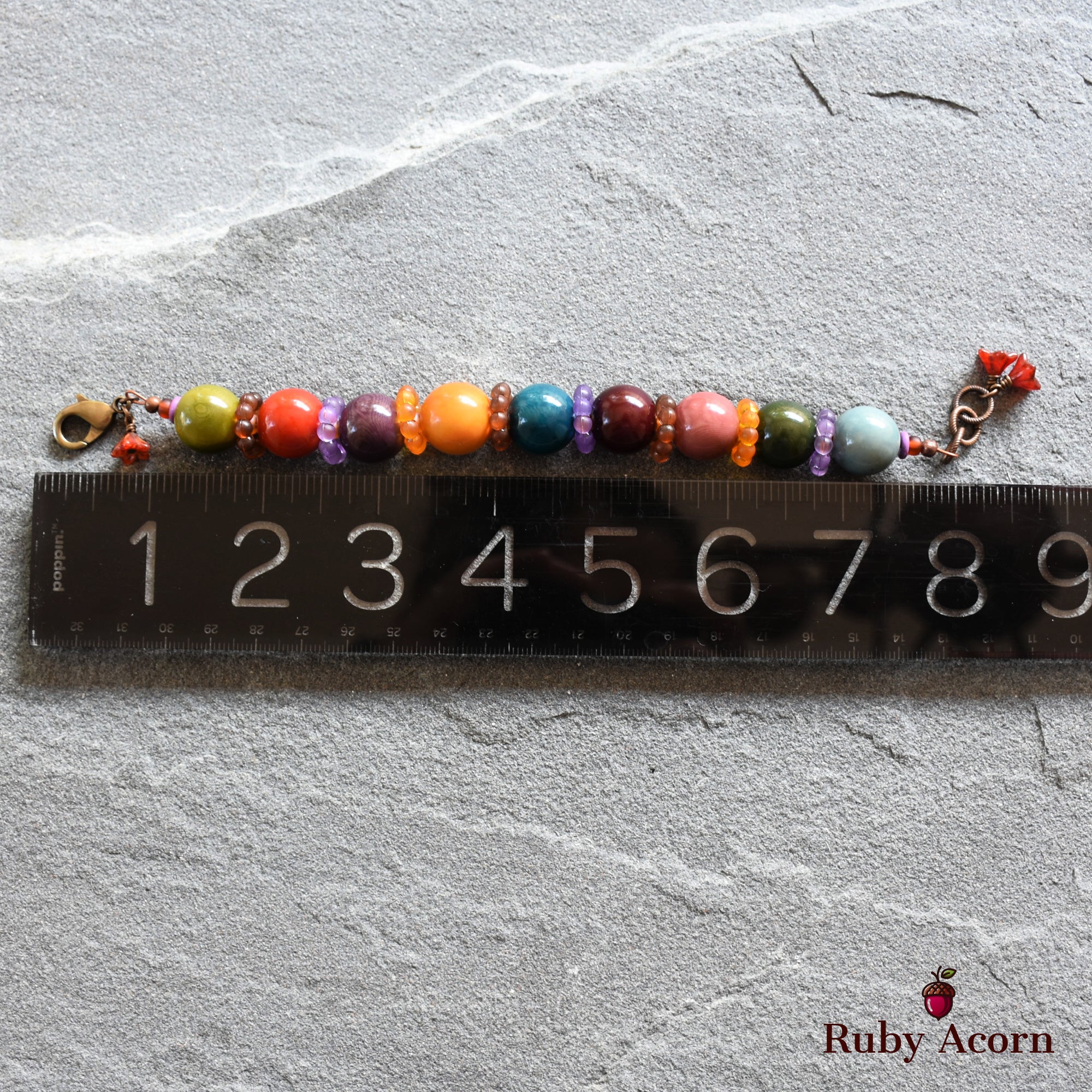 This image shows a bracelet. The length, measured against the ruler, is around 7 inches, which is typical for a bracelet. The colorful beads and the clasp also suggest it is designed to be worn around the wrist.