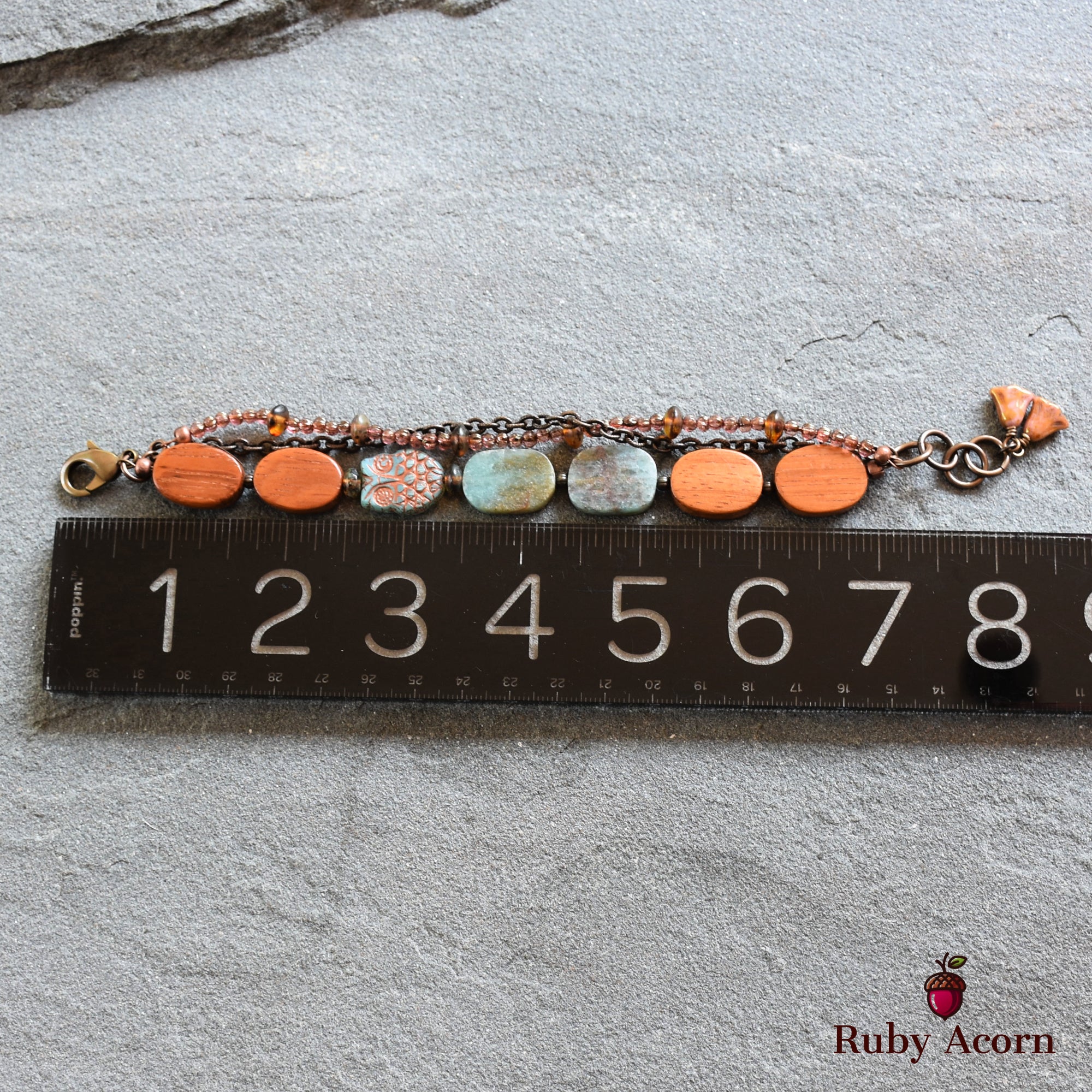 This image shows a bracelet. The jewelry is relatively short in length, as seen against the ruler, and it has a clasp on one end, typical of bracelets. The design includes beads and stones strung together.