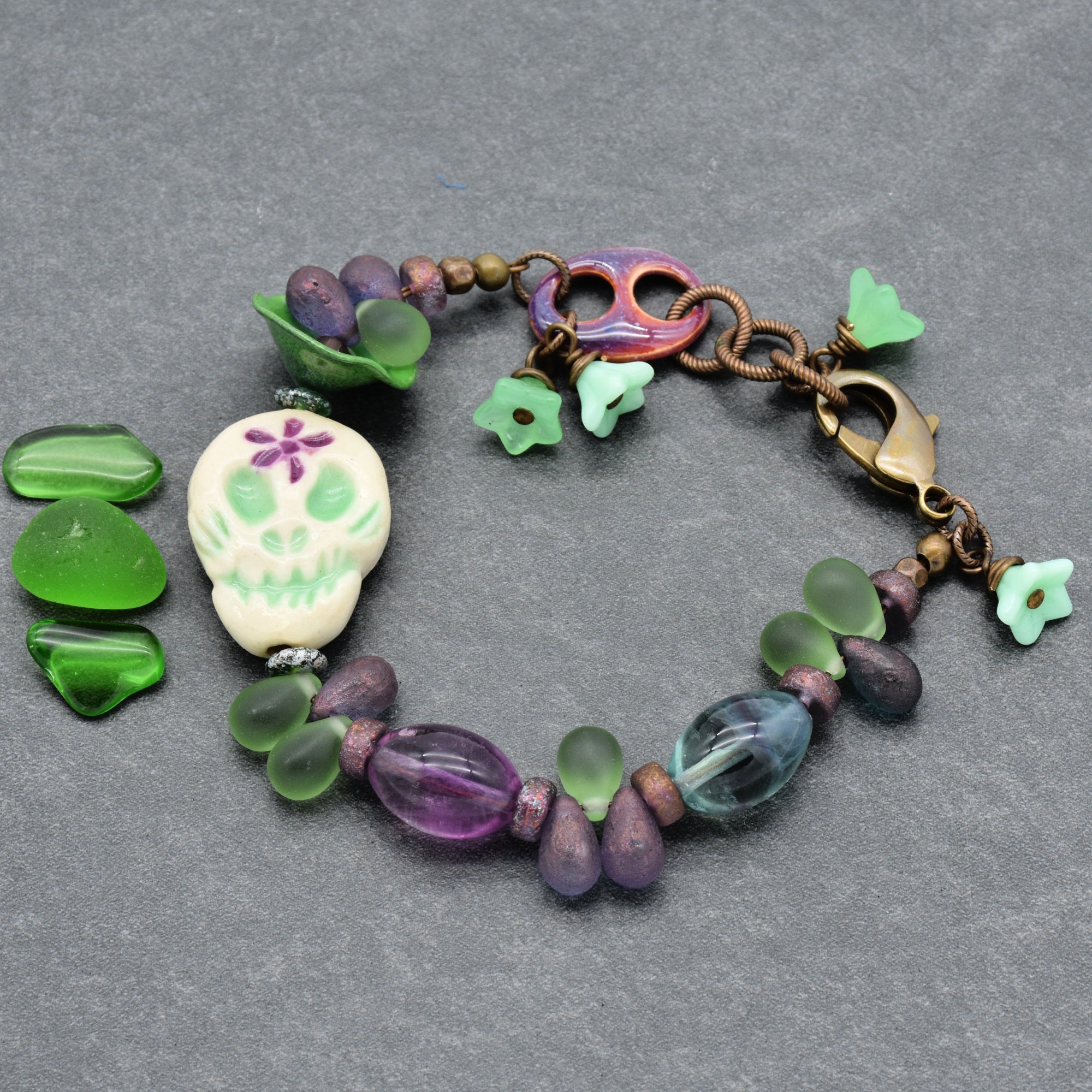 This image shows a bracelet. It has a circular shape with a clasp for fastening, featuring decorative beads and a skull charm.