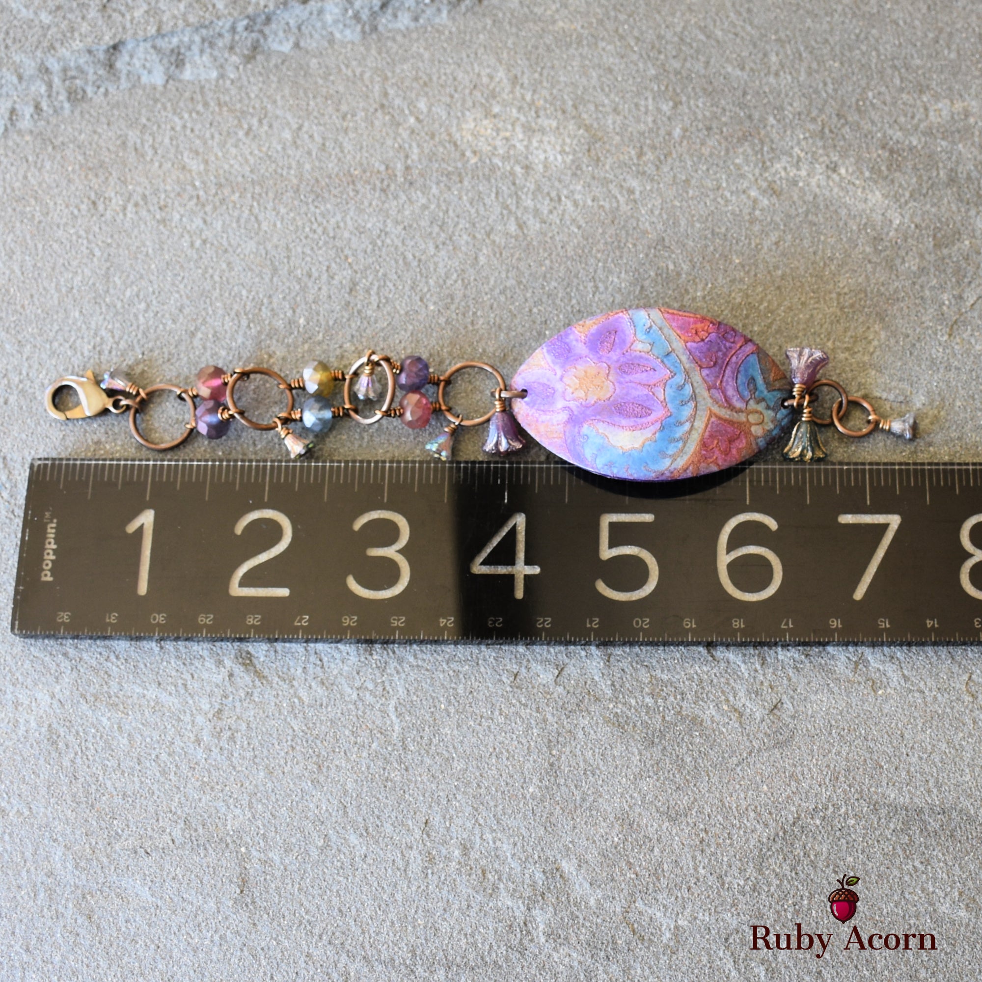 This image shows a bracelet. The length, the clasp style, and the size indicate that it is designed to be worn around the wrist. The ruler confirms the size is consistent with a bracelet rather than a necklace or earring.