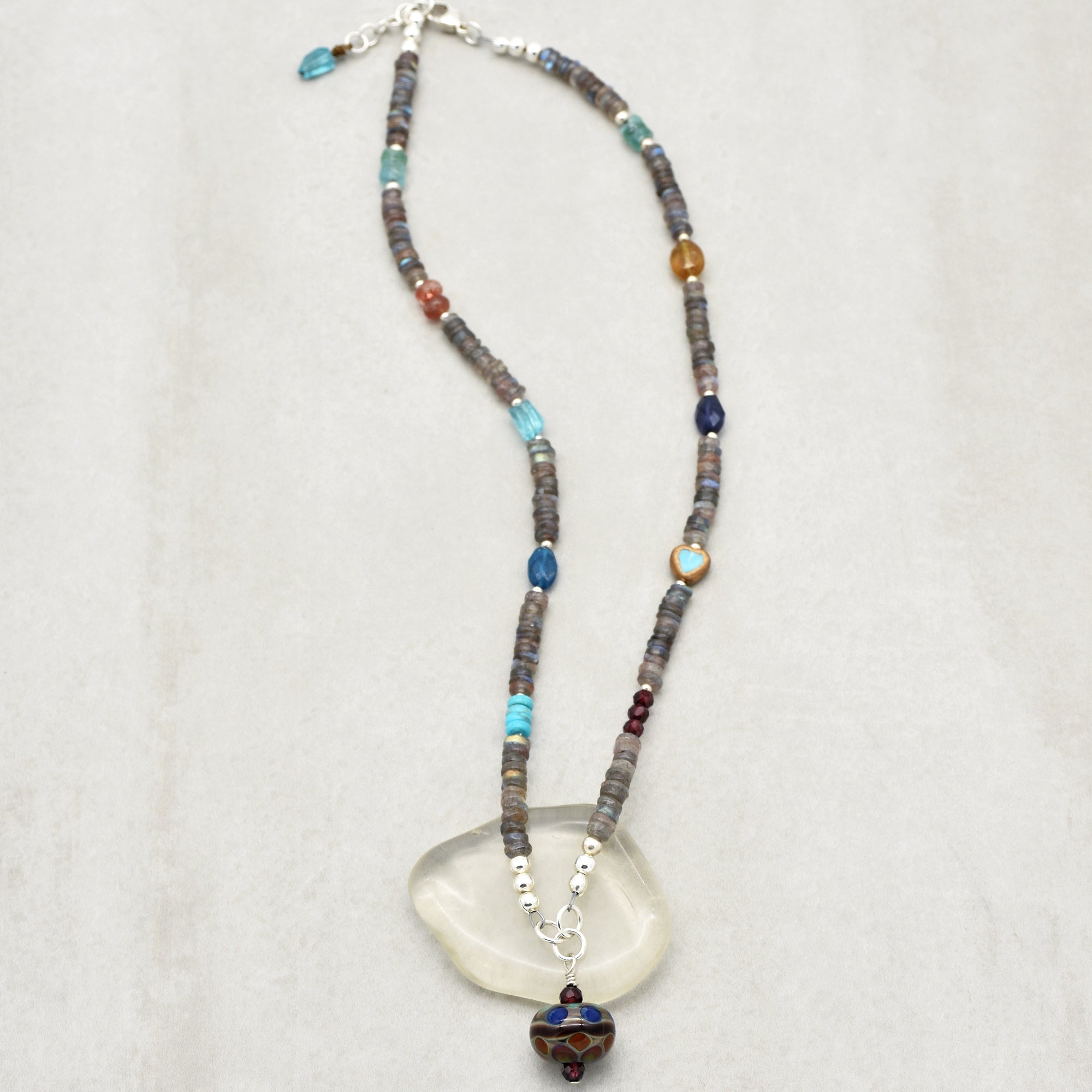 This image shows a necklace. The jewelry has a string of beads and a larger decorative pendant at the bottom center, which is characteristic of a necklace.