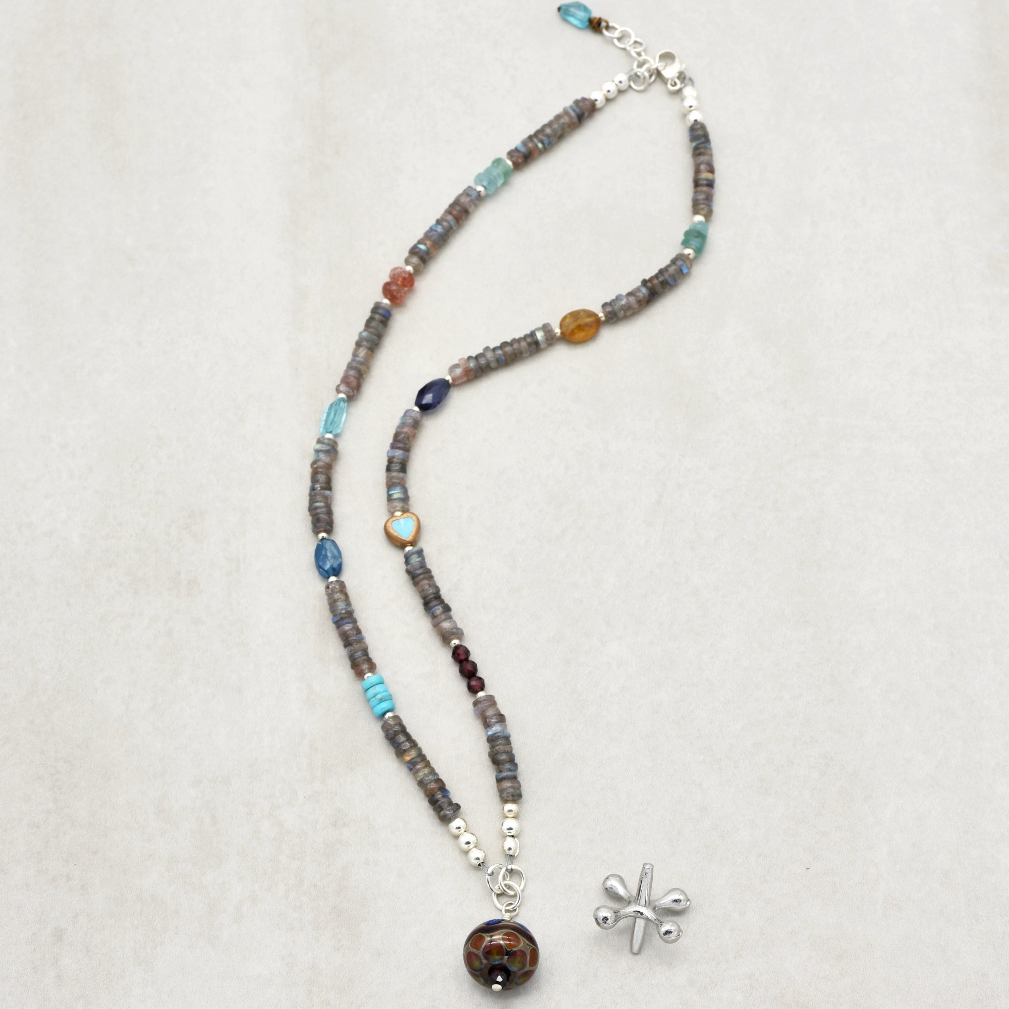 This image shows a necklace. The length, the clasp, and the arrangement of beads including a central pendant all suggest that it is a necklace rather than an earring or bracelet.