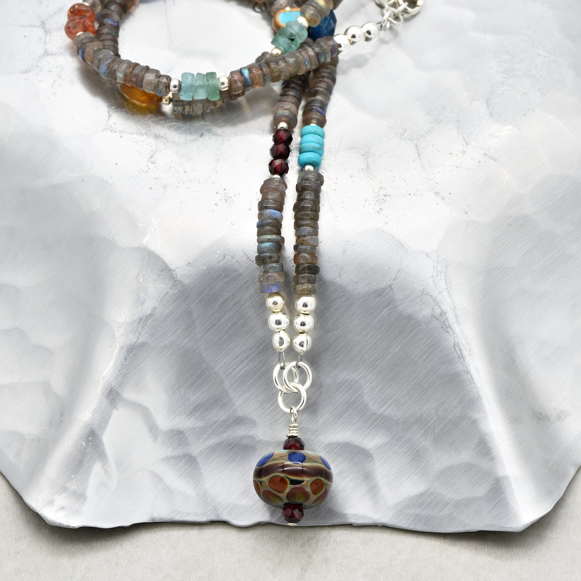 The image shows a piece of jewelry that is a necklace. The beads are strung together with a decorative pendant at the end. The length and design suggest it is not an earring or bracelet but rather a necklace.