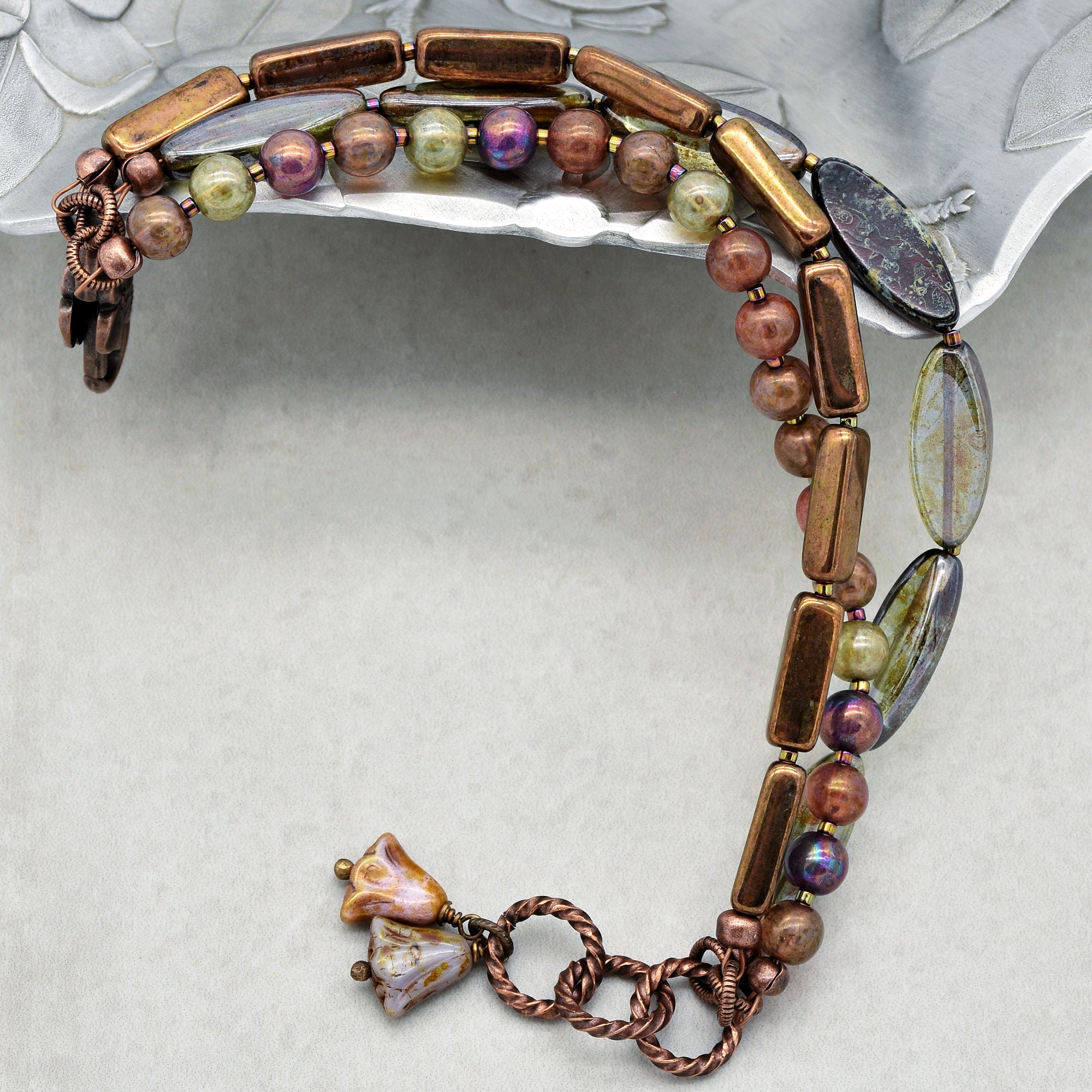 This image shows a bracelet. The jewelry in the image is circular and of a size that fits around a wrist. It features various beads and decorative elements, with a clasp visible on one end, which is typical of bracelets.
