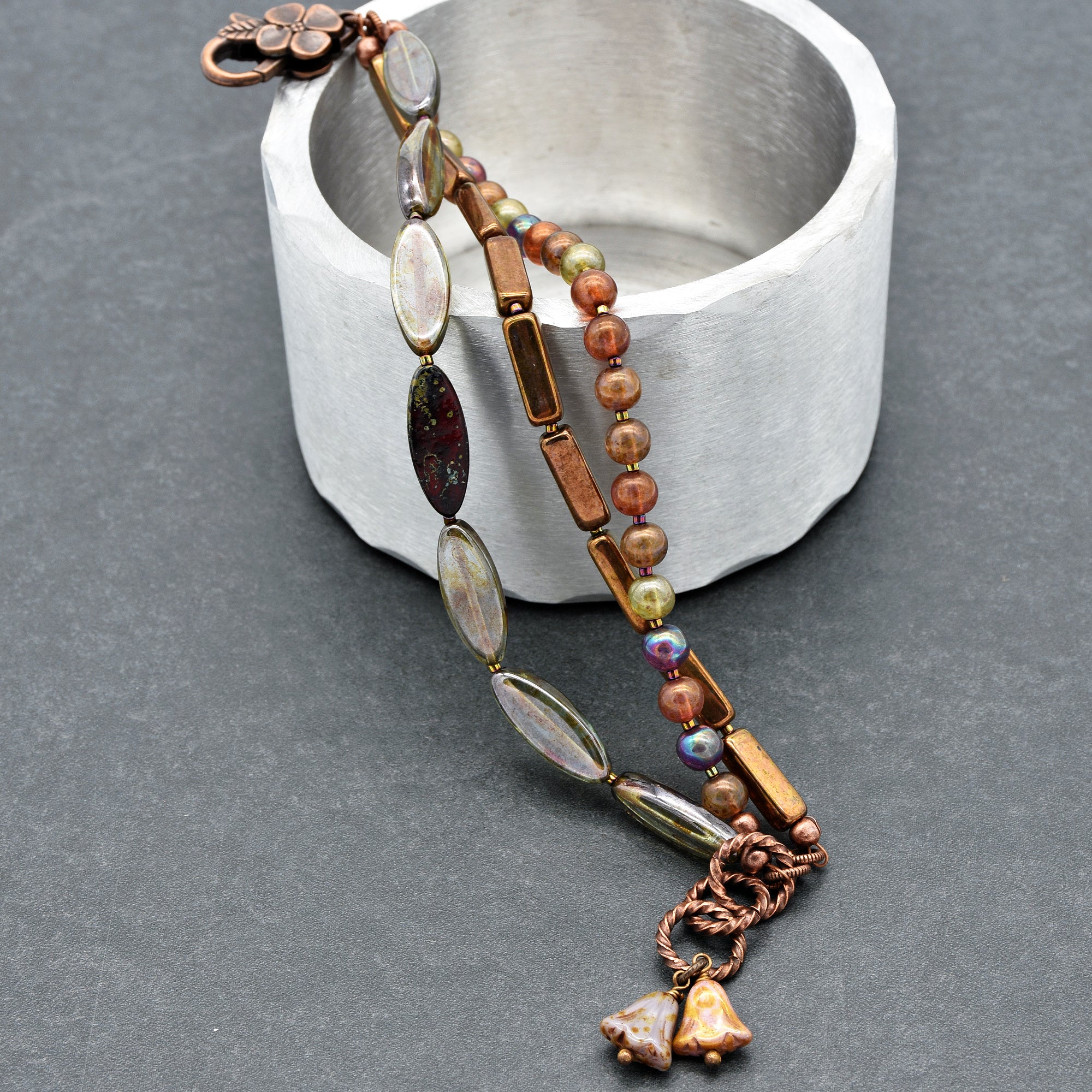 This image shows a bracelet. You can tell by its size and the way it is designed with a clasp that is suited for wrapping around a wrist. The beads and ornamental elements are arranged in a way typical for bracelets.