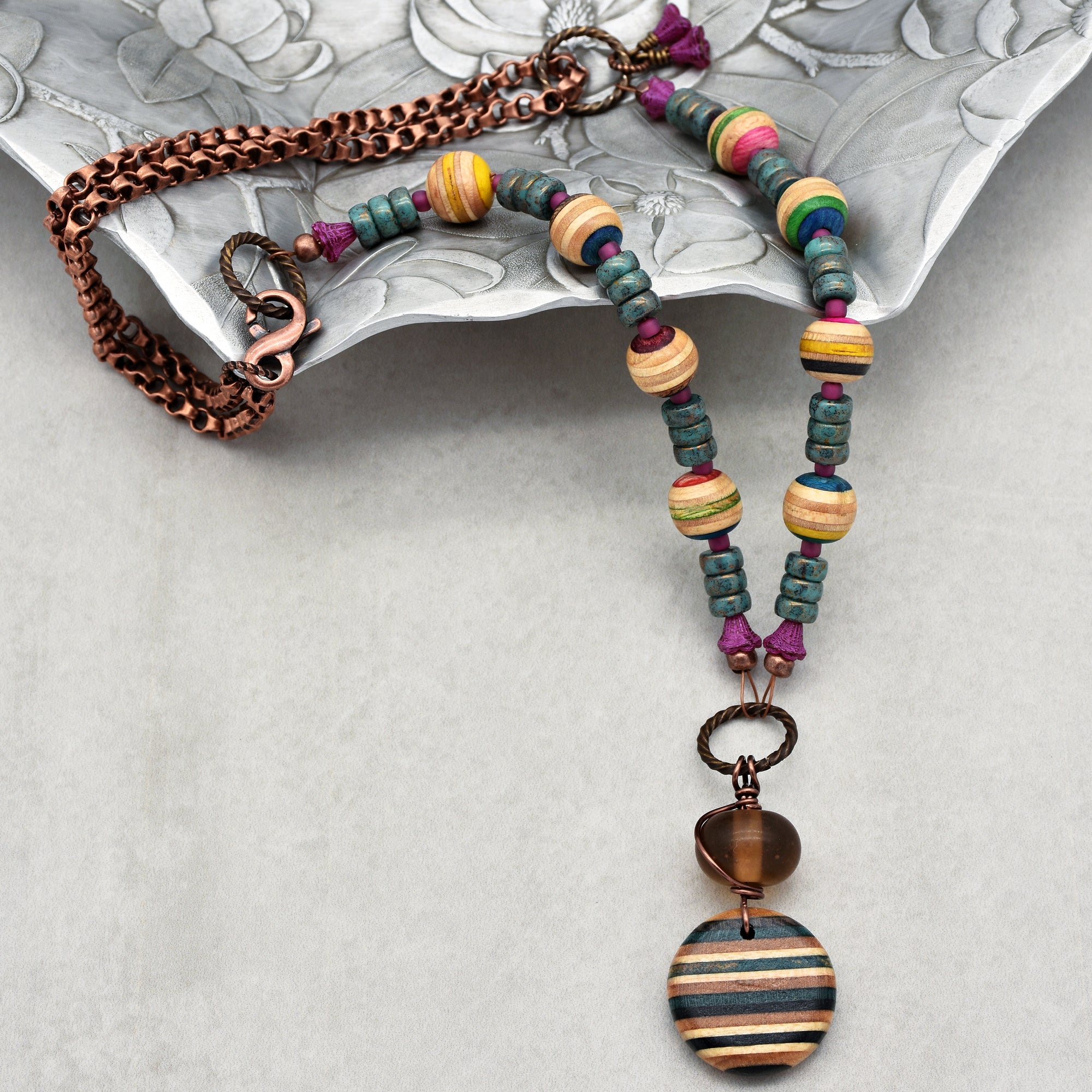 This image shows a necklace. It features a chain and colorful beads with a pendant at the bottom.