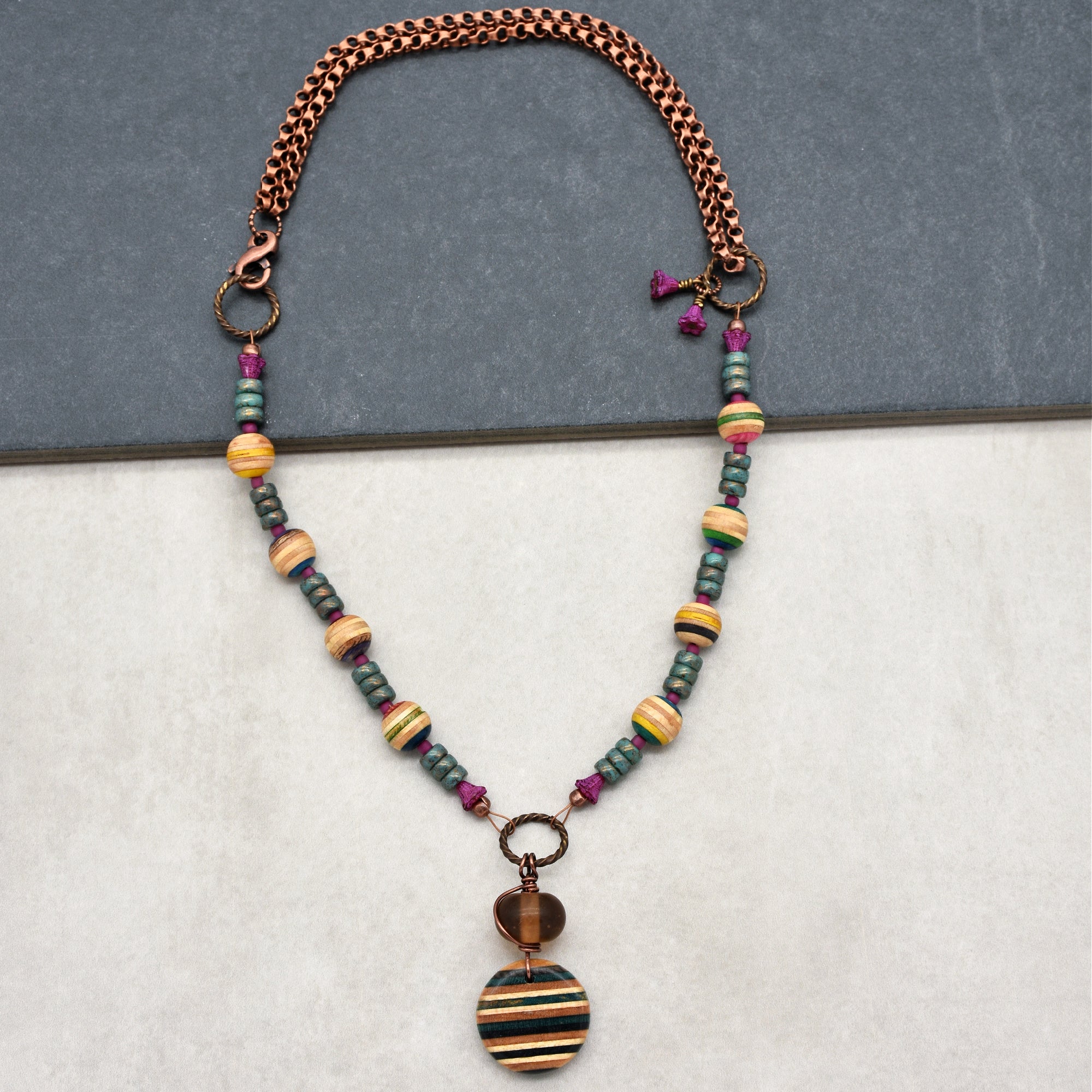This image shows a necklace. The jewelry piece has a chain with colorful beads and a pendant hanging at the center, which is typical of a necklace design.