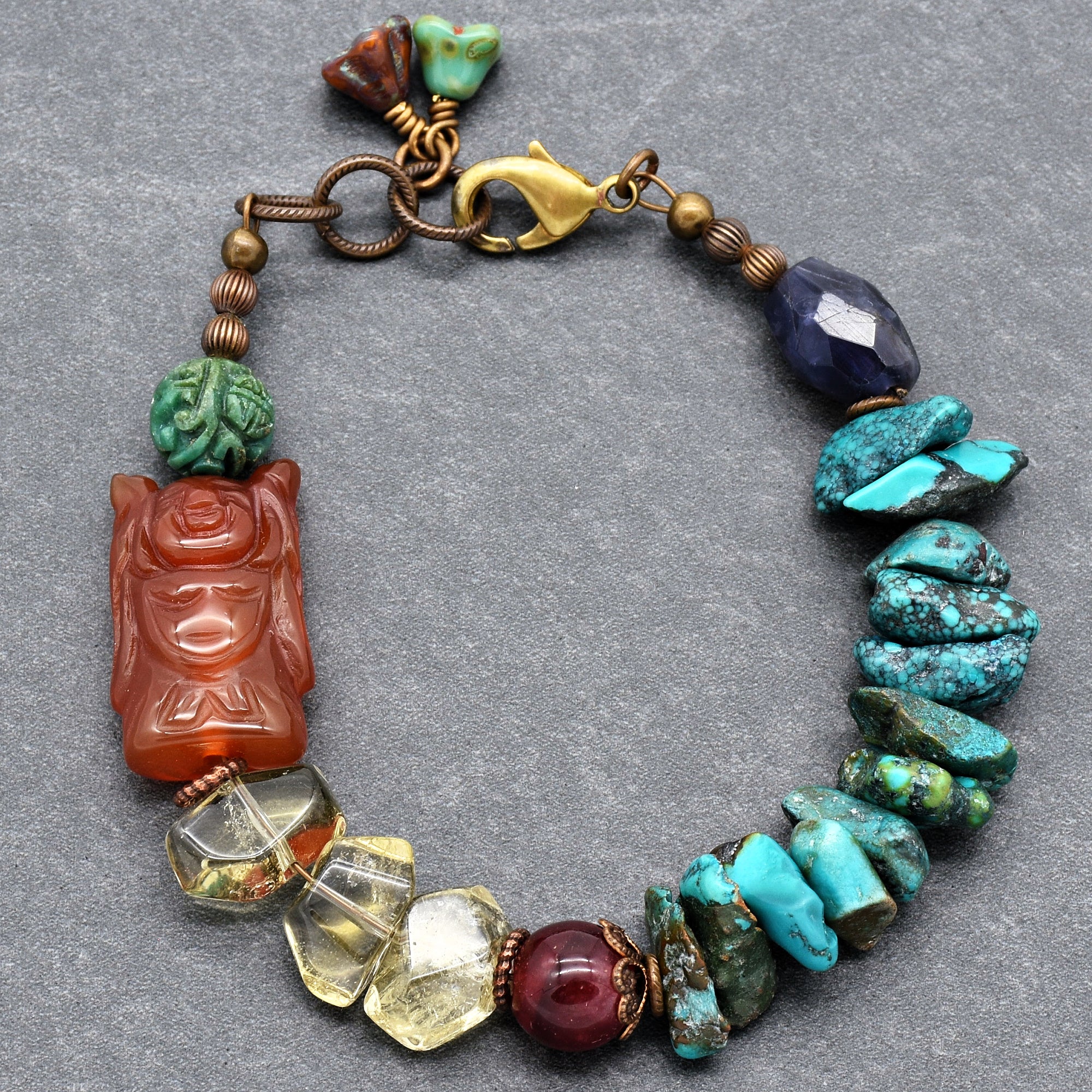 This image shows a bracelet. The jewelry is circular and designed to fit around the wrist, with a clasp visible at the top for fastening. The bracelet features a variety of beads and stones in different shapes and colors.