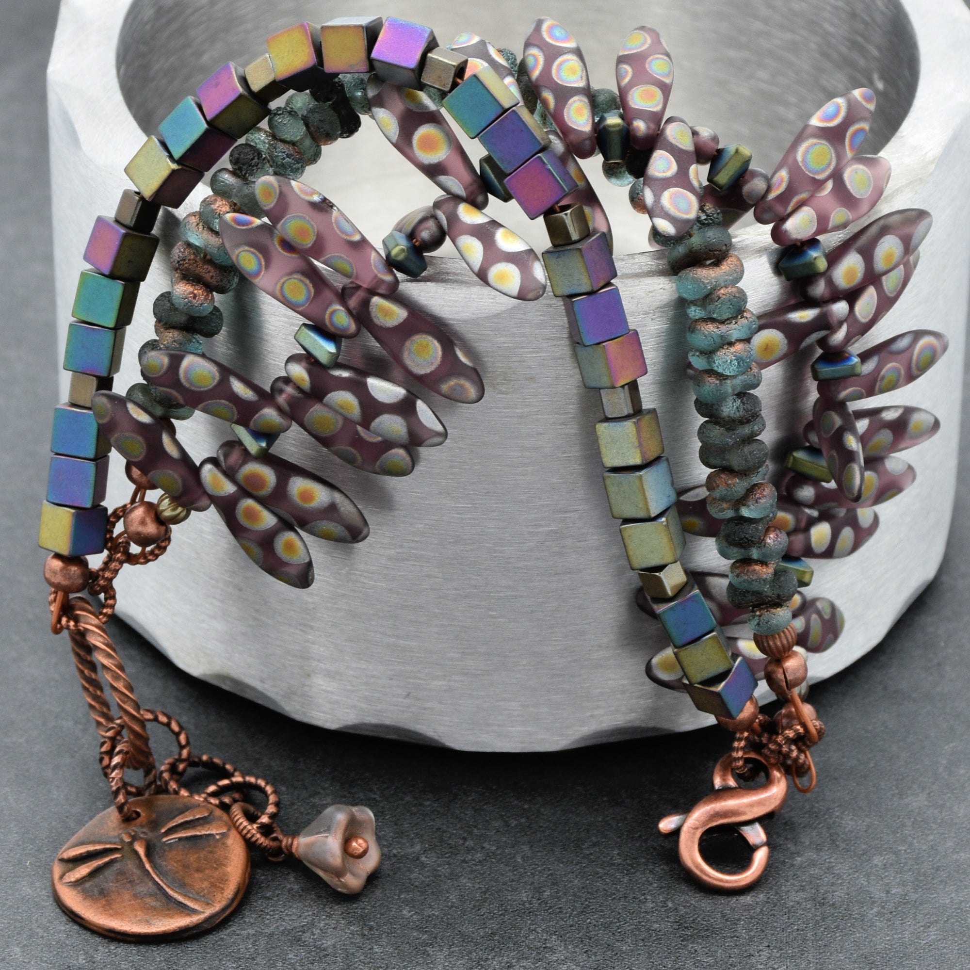 This image shows a bracelet. The jewelry piece is coiled with beads and an ornamental copper charm featuring a dragonfly design, along with a lobster clasp, which is typical for bracelets.