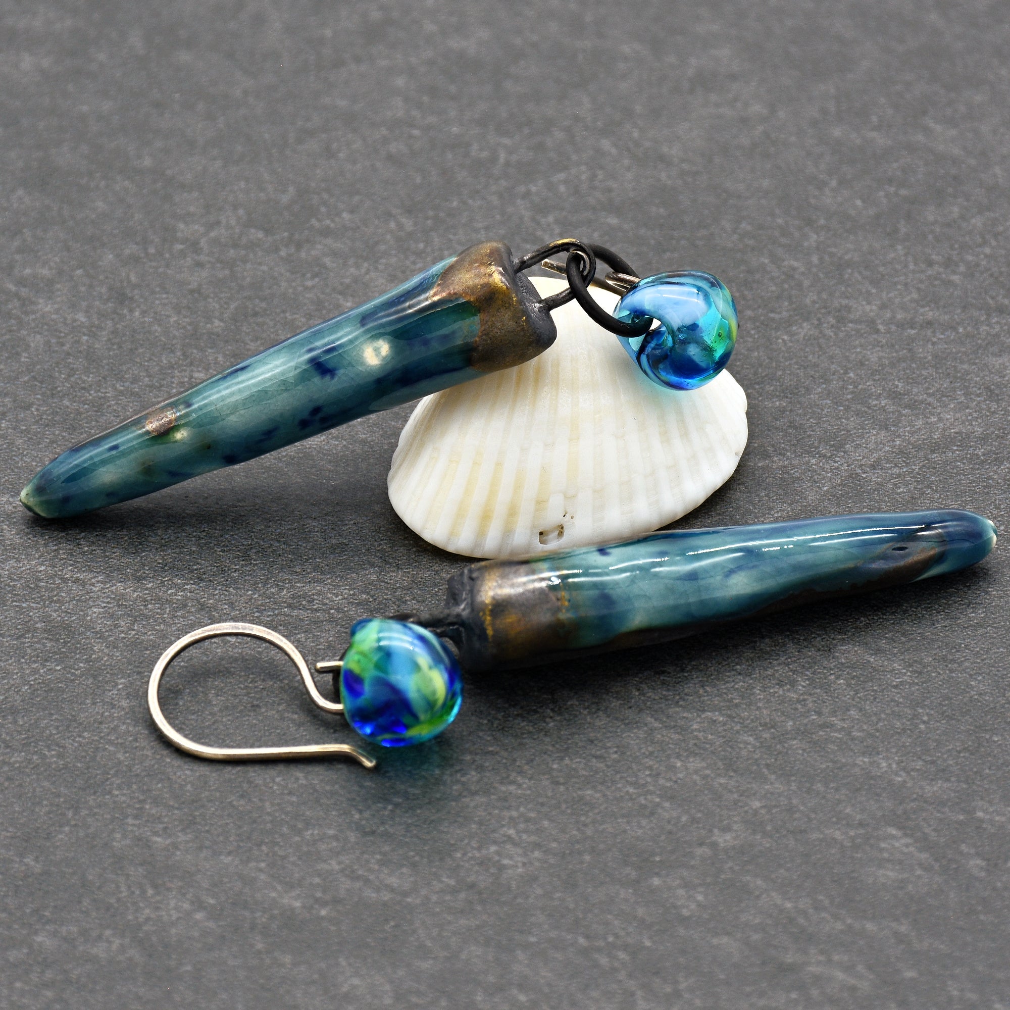 The jewelry in the image is a pair of earrings. They have blue and green beads attached to elongated blue pendants with metal hooks for wearing.