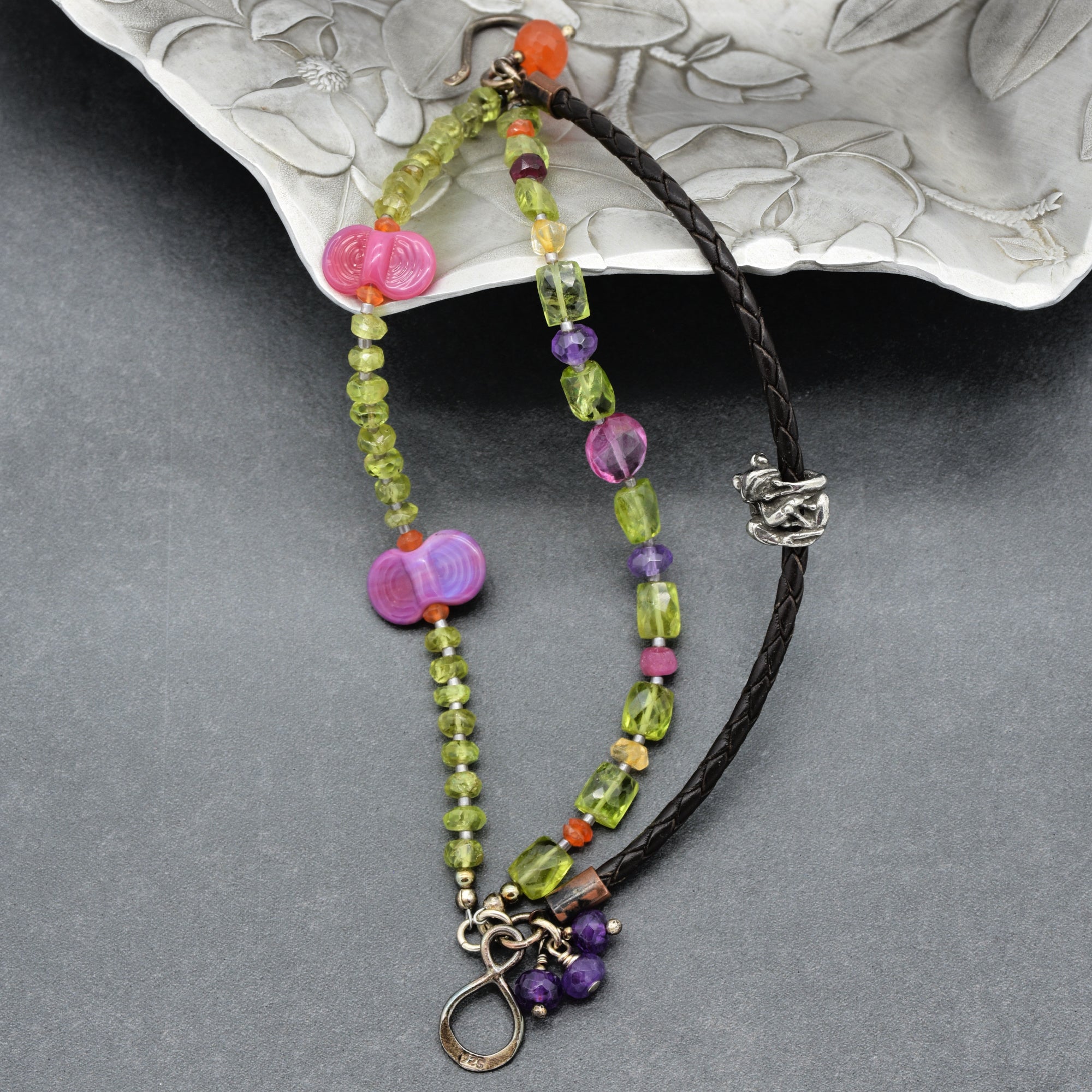 The jewelry in the image is a bracelet. The length, clasp, and overall design with beads and a braided leather section suggest it is intended to be worn around the wrist.