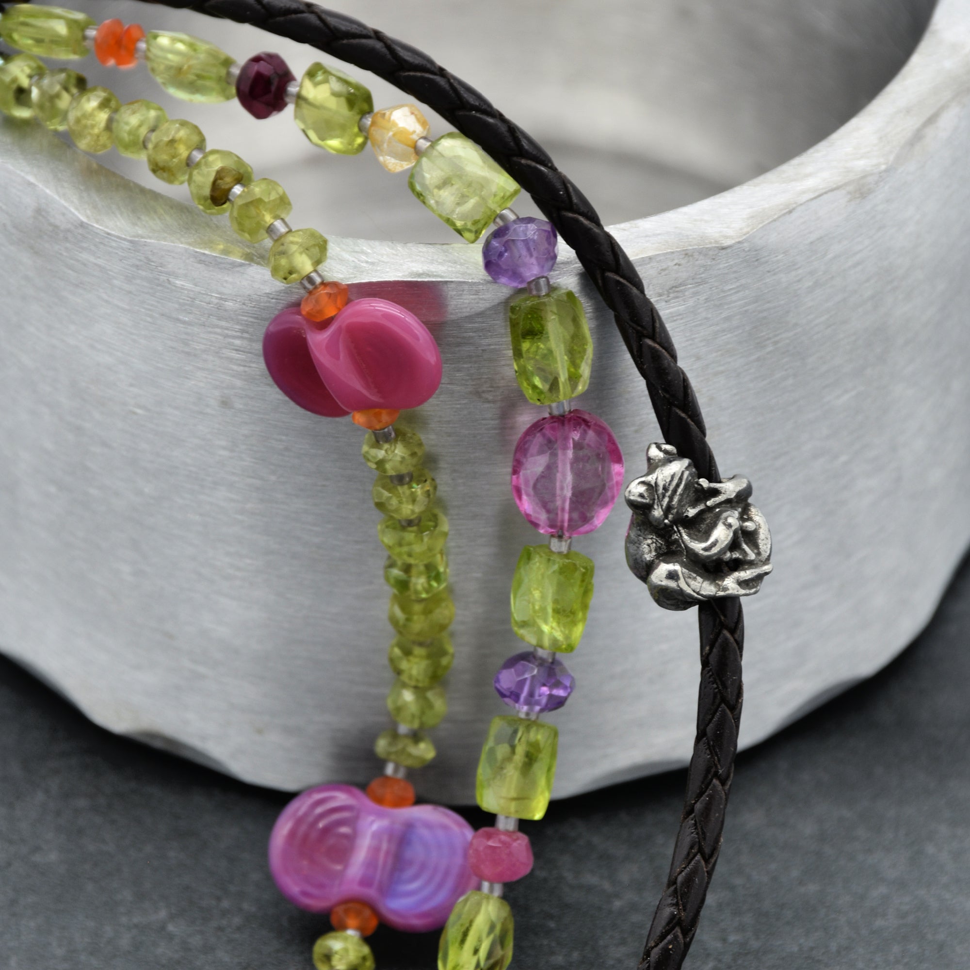 This image shows a bracelet. The braided leather strap with a decorative metal clasp is characteristic of a bracelet design. The beaded strands alongside suggest it's a multi-strand bracelet. Necklaces and earrings typically have different structural elements.