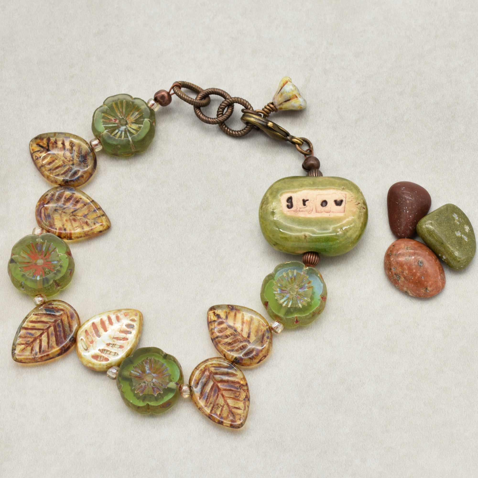 This image shows a bracelet. The jewelry piece is circular and composed of beads and decorative elements, including a prominent bead with the word "grow" on it, typical of bracelet design.