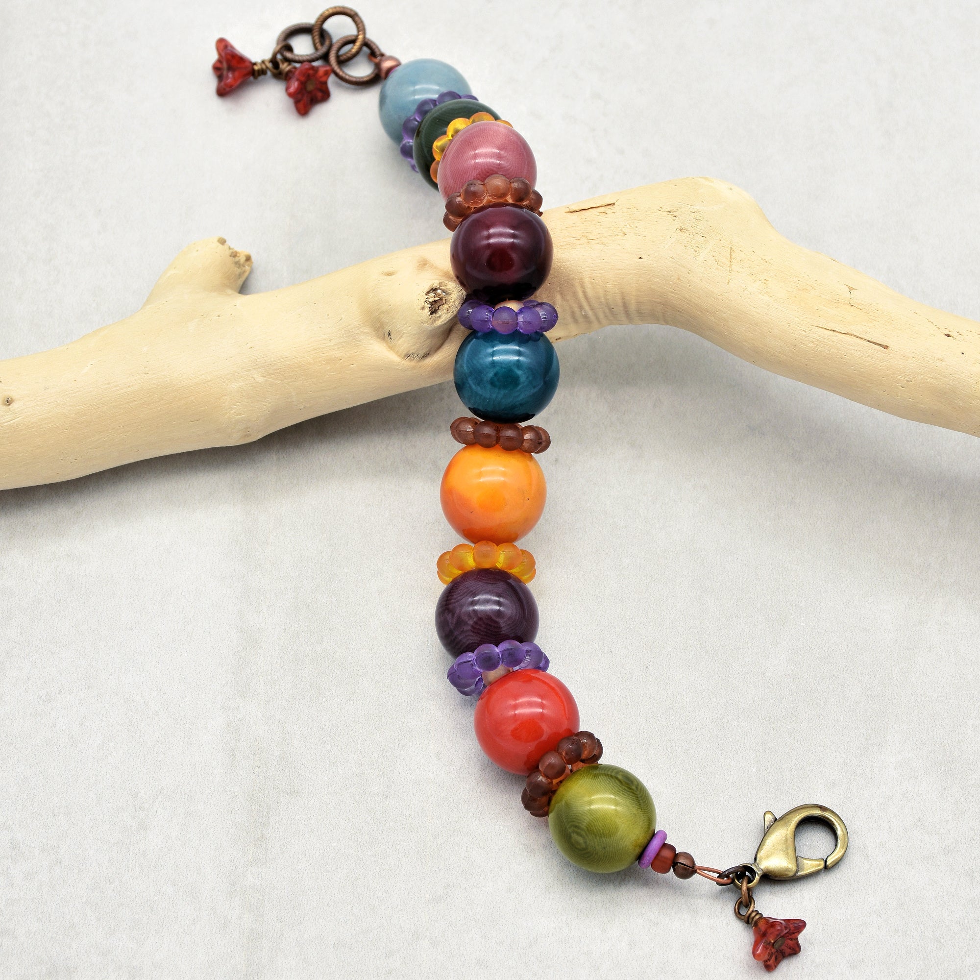This image shows a bracelet. It consists of large, colorful beads separated by smaller decorative beads. There is also a clasp at one end, which is typically used for bracelets to secure them around the wrist.