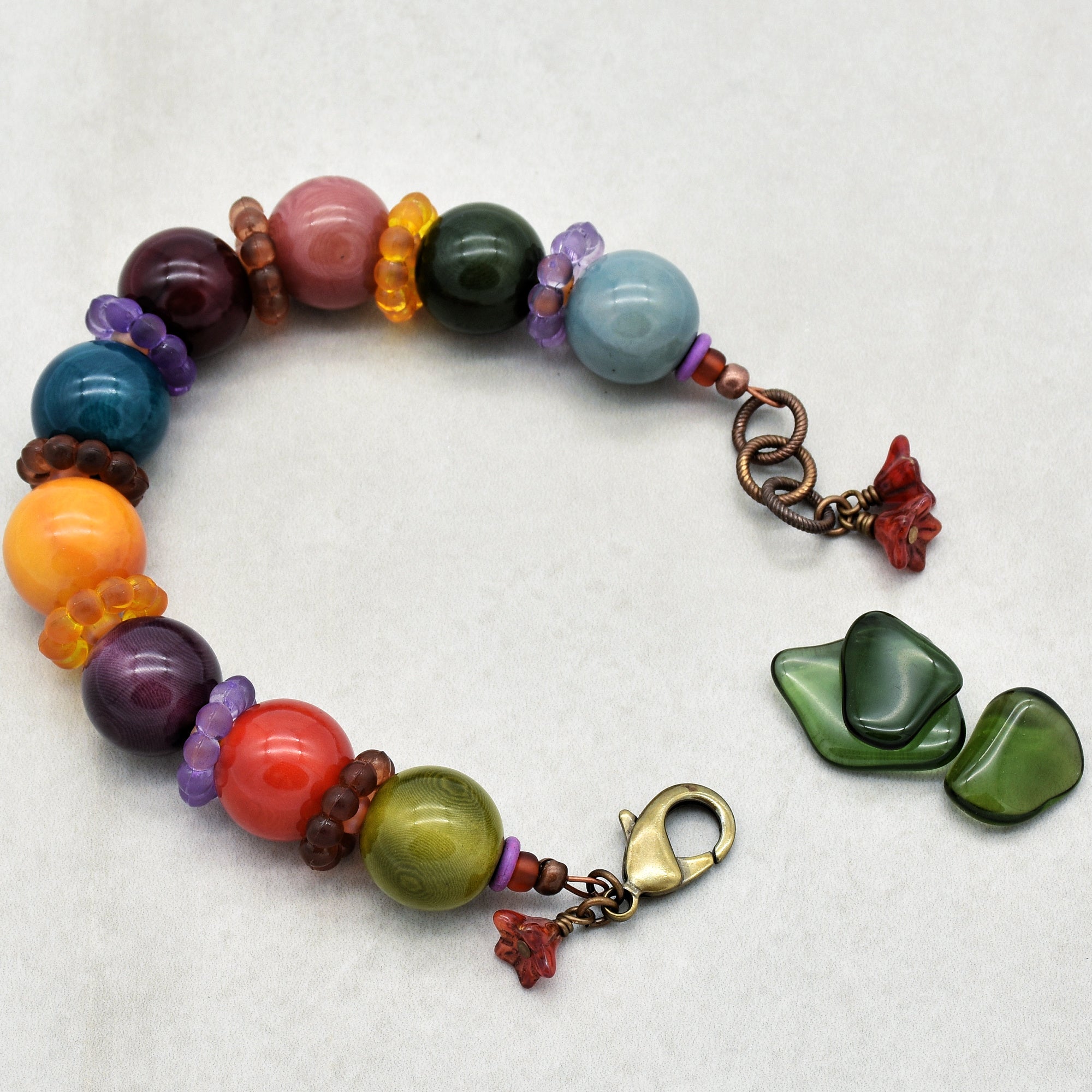 This image shows a bracelet. It is made of large colorful beads interspersed with smaller decorative beads, and it has a clasp for fastening around the wrist. The size and design, including the clasp, indicate it is intended to be worn as a bracelet rather than a necklace or earring.
