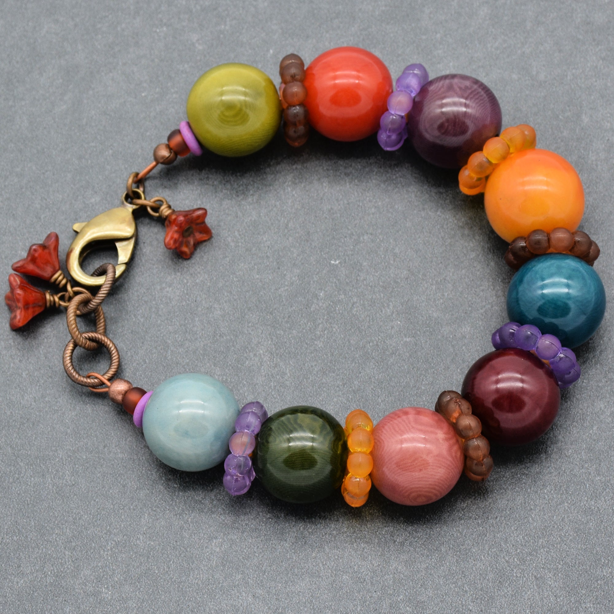 This image shows a bracelet. It has a circular shape and a clasp, which are typical characteristics of a bracelet. The colorful beads and small flower-shaped charms add to its decorative design.