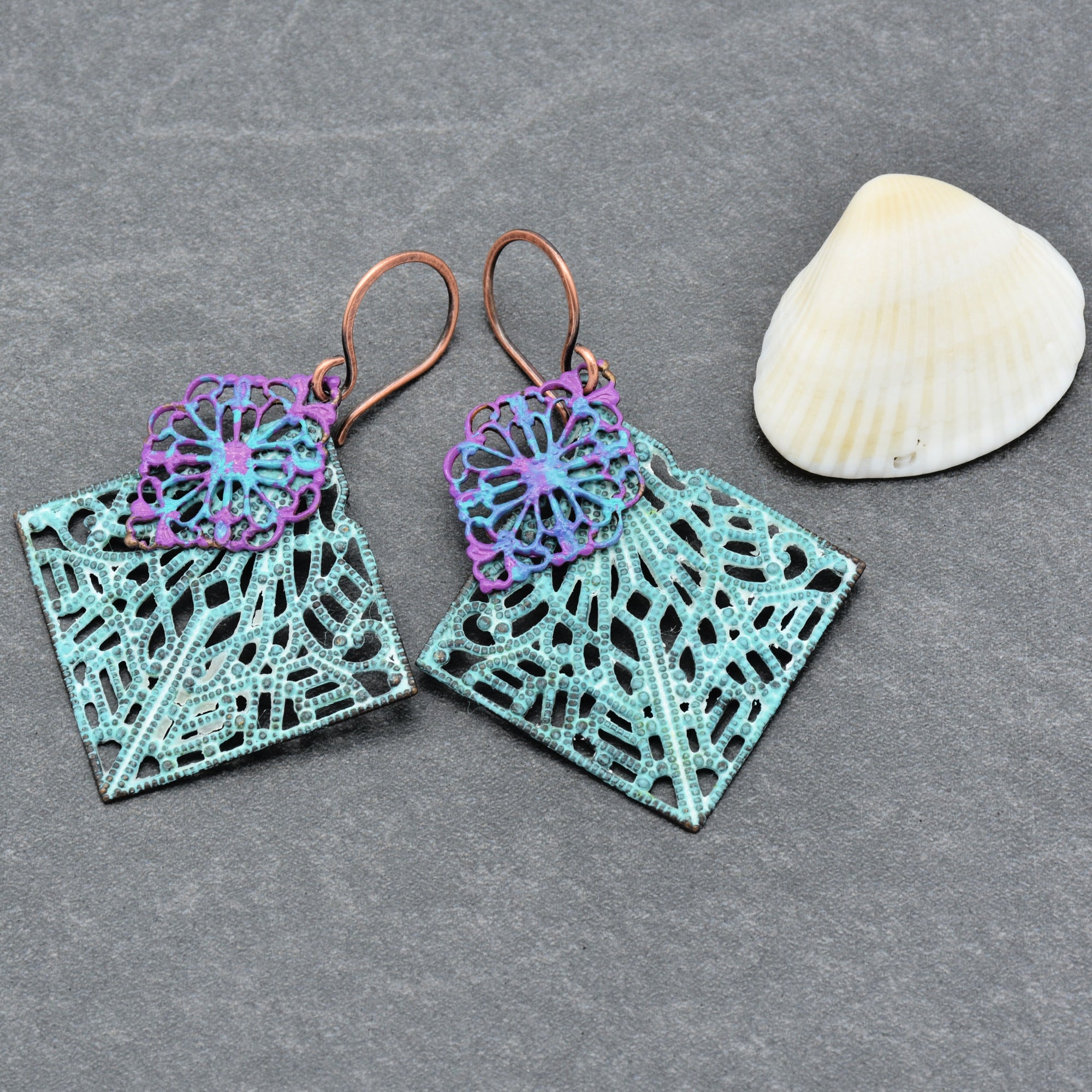 The image shows a pair of earrings. They have intricate, colorful designs with square shapes and are equipped with hooks for wearing on ears.