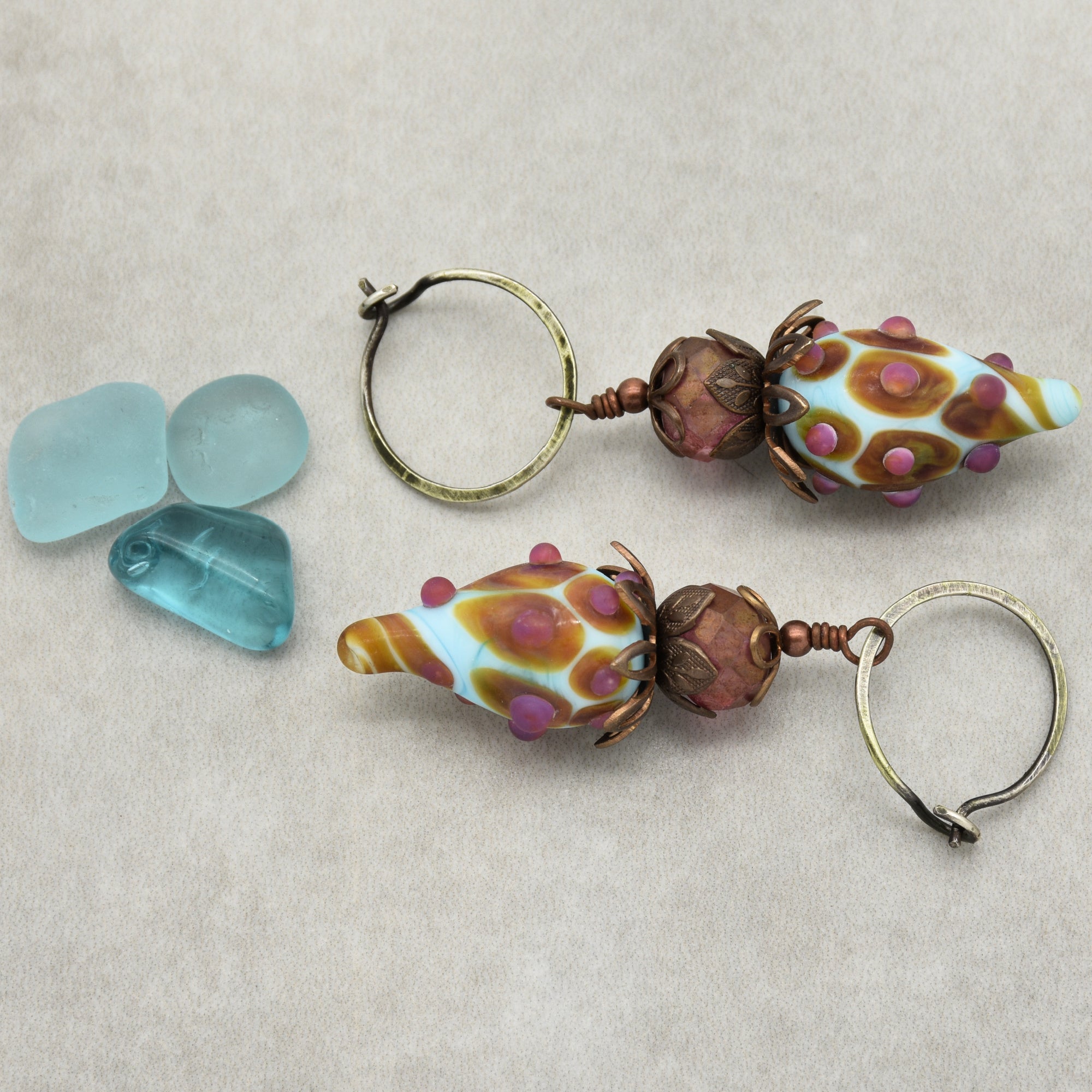 The image shows a pair of earrings. They have hoops with decorative beads attached.