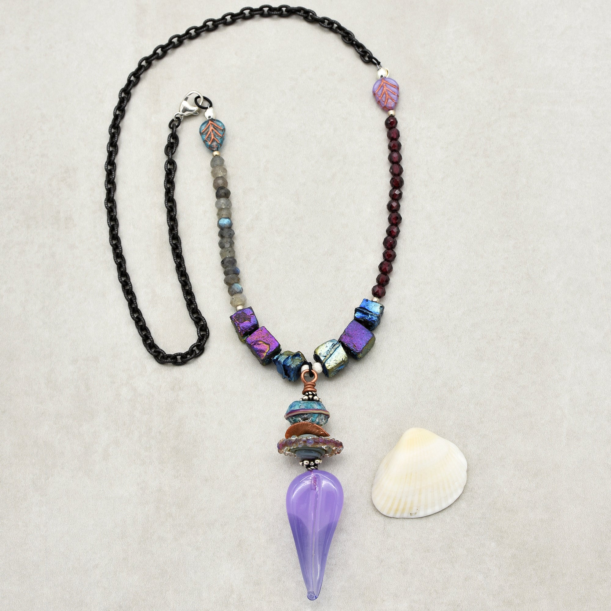 The jewelry in the image is a necklace. It has a black chain and features various beads and a distinctive purple pendant at the center.