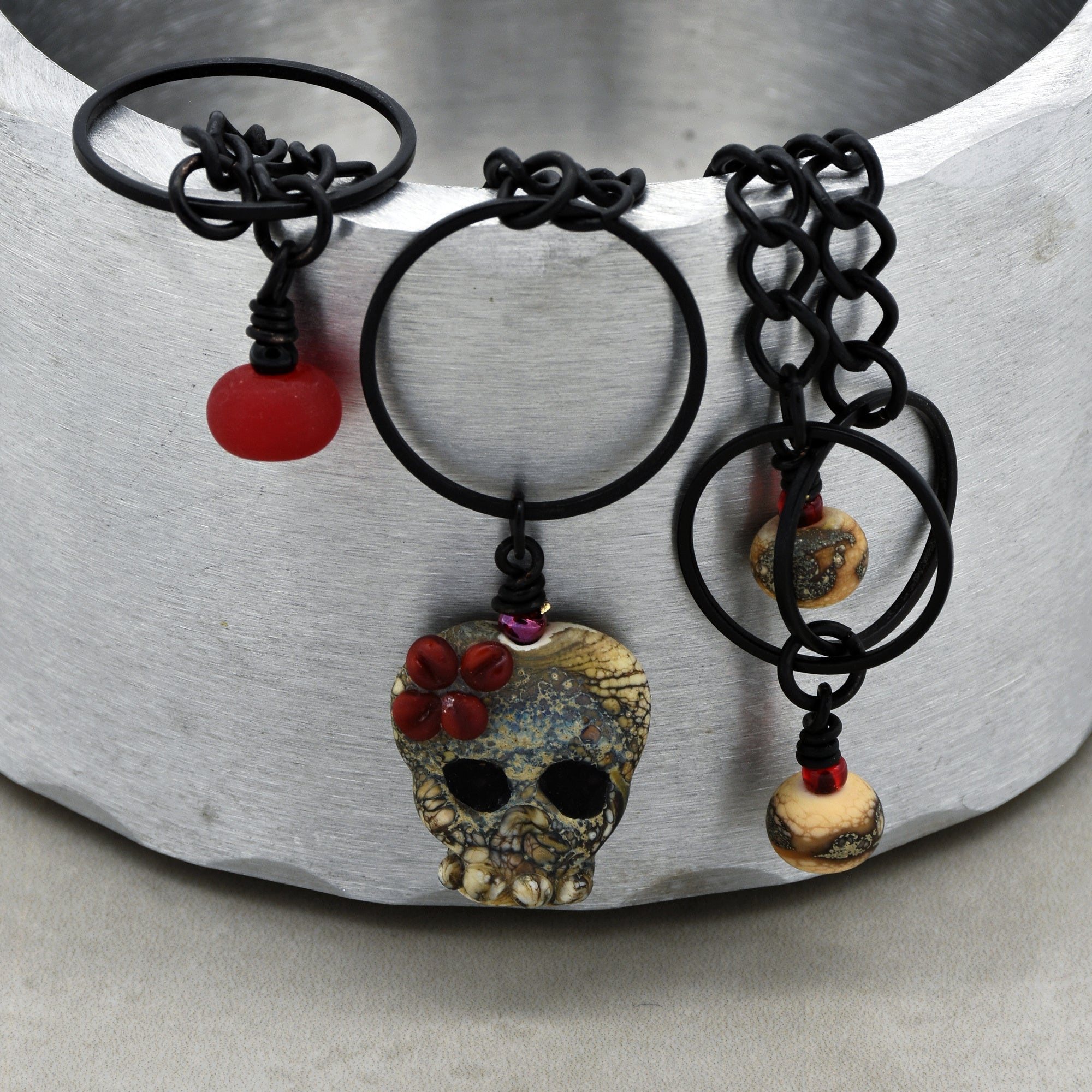 This image shows a pair of earrings. You can identify them by the matching pairs and the size typical of earrings, including the earring hooks and decorative elements like the skull and beads.