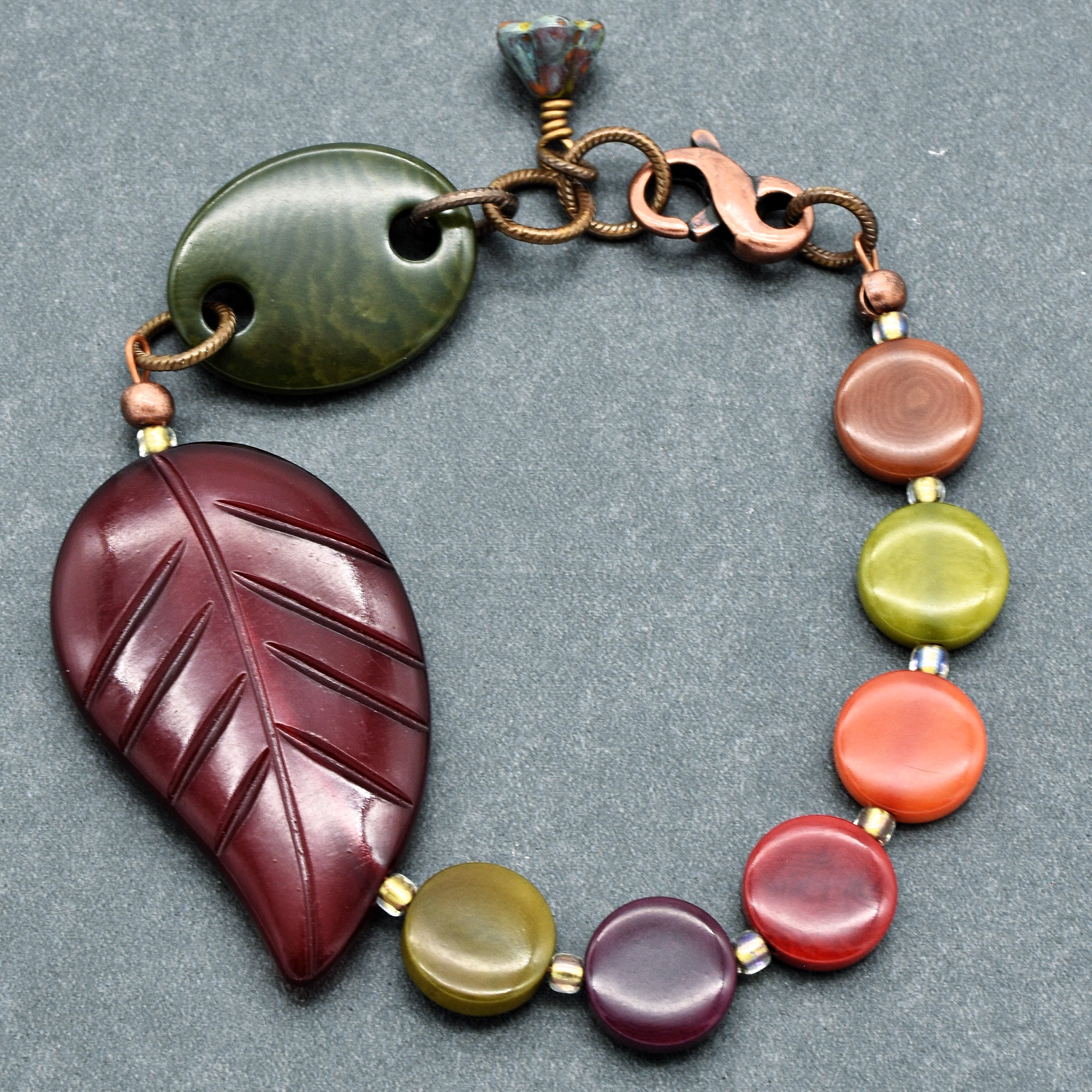 This image shows a bracelet. The size and shape, along with the clasp, are typical of a bracelet rather than a necklace or an earring. The design includes colorful beads and a large leaf-shaped bead, which are common elements in bracelet jewelry.