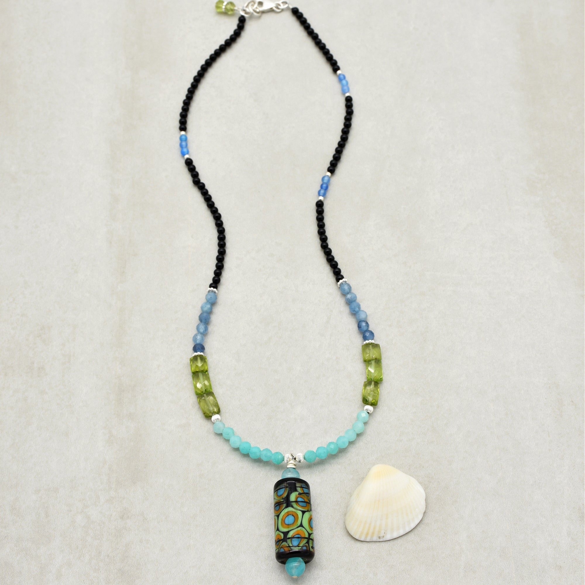 This jewelry appears to be a necklace. The length, the pattern of beads, and the central pendant suggest that it is designed to be worn around the neck.