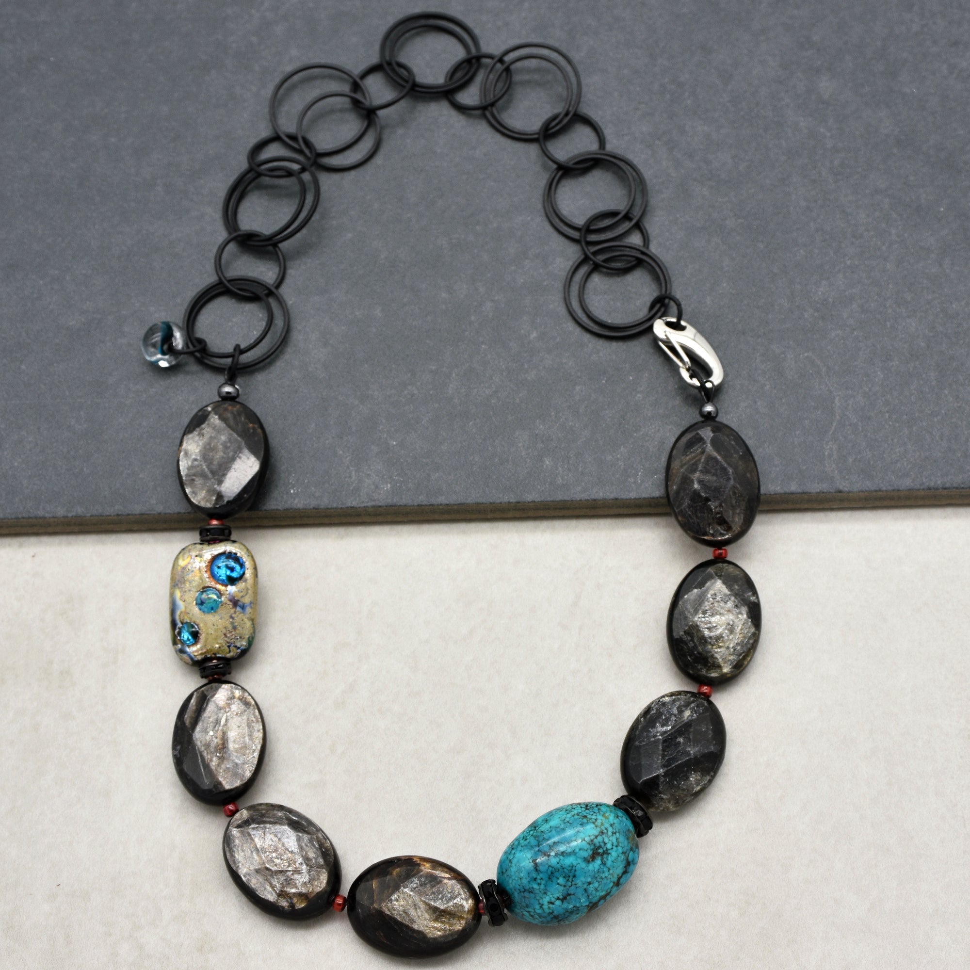This image shows a necklace. The jewelry piece has larger beads spaced along the chain and a clasp, which is characteristic of a necklace rather than an earring or bracelet. The size and arrangement of the beads also support it being a necklace.
