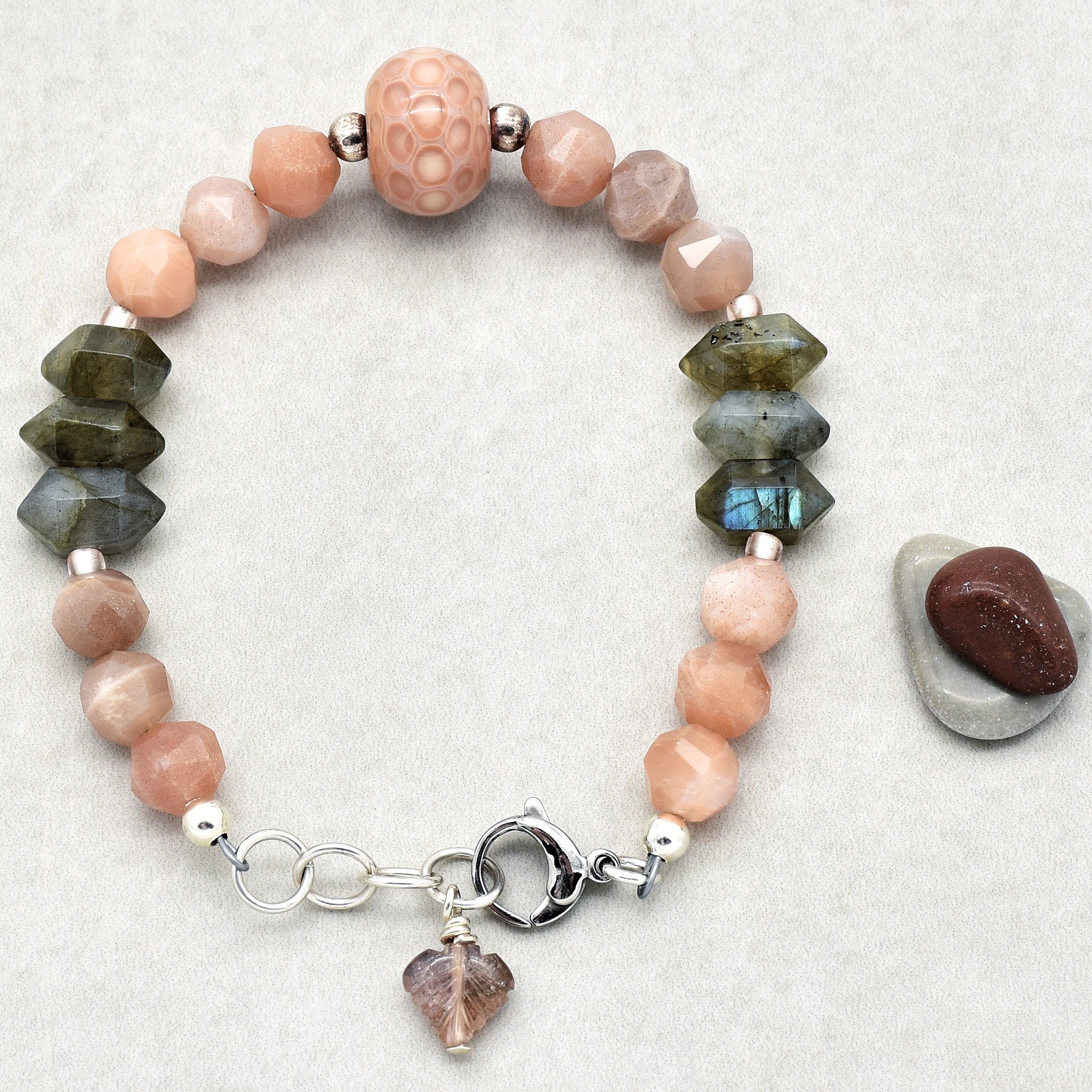 This image shows a bracelet. You can tell because of its circular shape sized to fit around a wrist, as well as the clasp designed to fasten the bracelet securely. The beads and charm also align with typical bracelet designs.