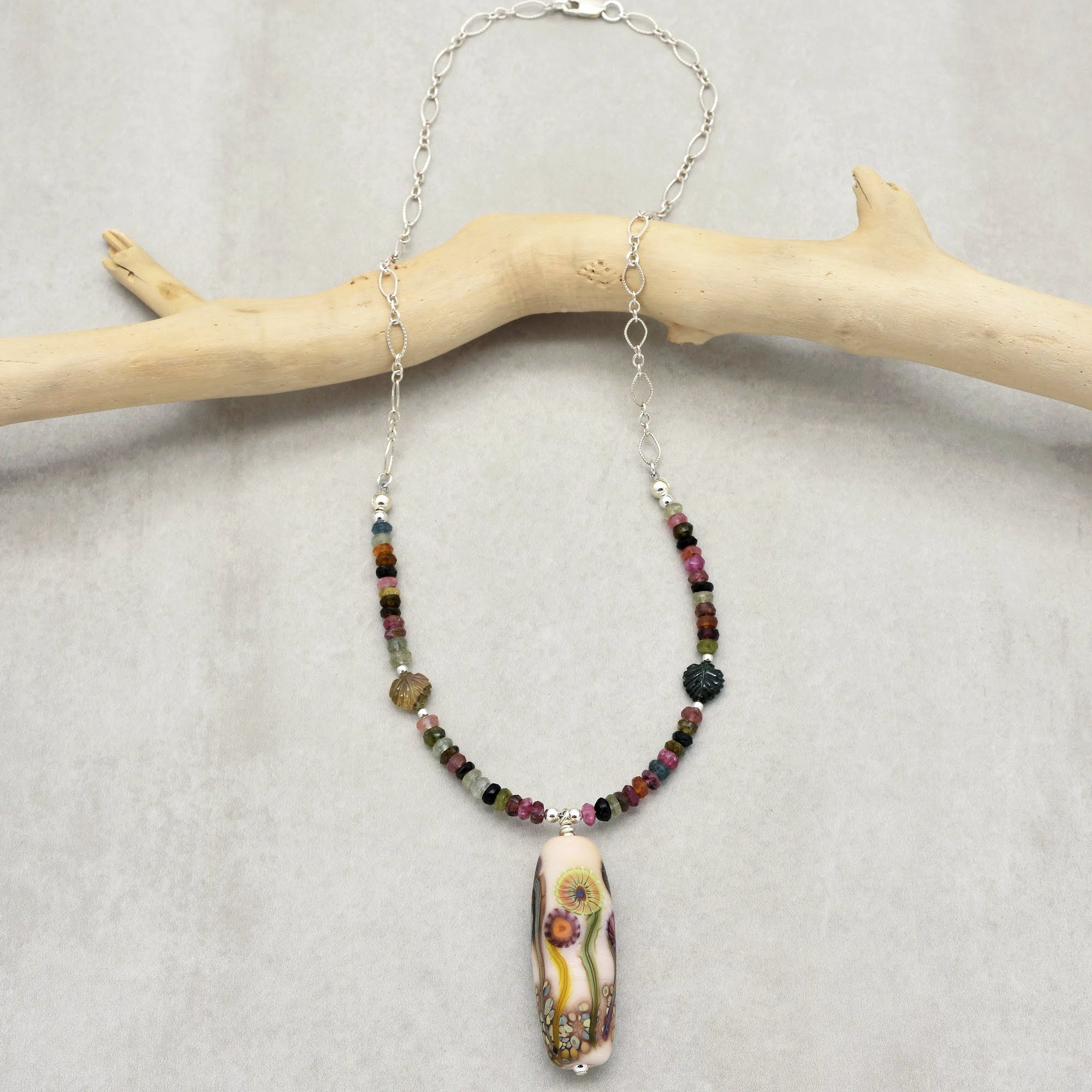 This image shows a necklace. The jewelry features a chain with small colorful beads and a large, decorative pendant hanging in the center. The length and design indicate it is a necklace rather than an earring or bracelet.