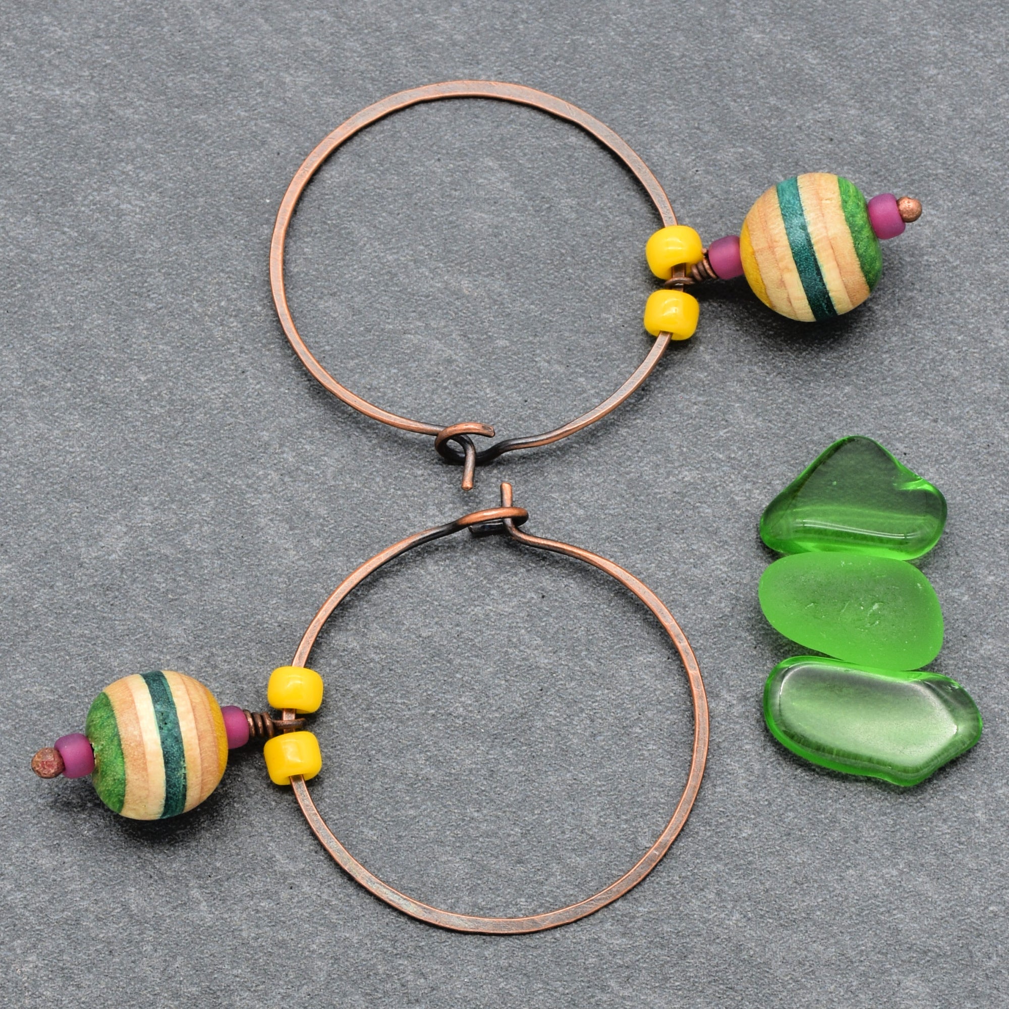 This image shows a pair of earrings. They are circular hoops with colorful beads attached, indicating they are designed to be worn on the ears.