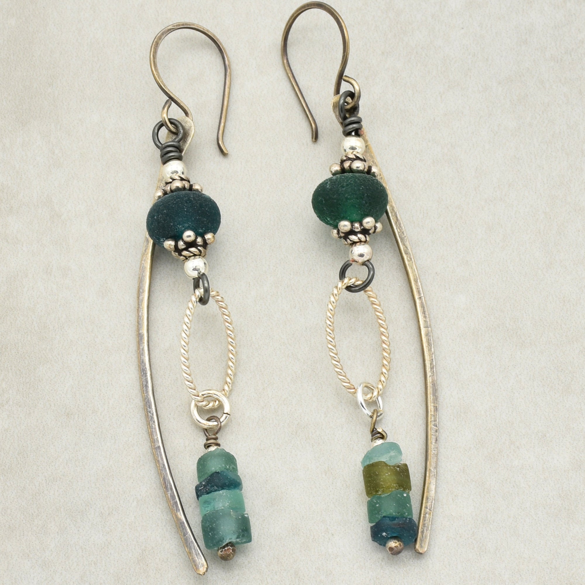 This image shows a pair of earrings. They have hook-style backs, a central bead with decorative metal accents, and dangling colorful beads at the bottom.