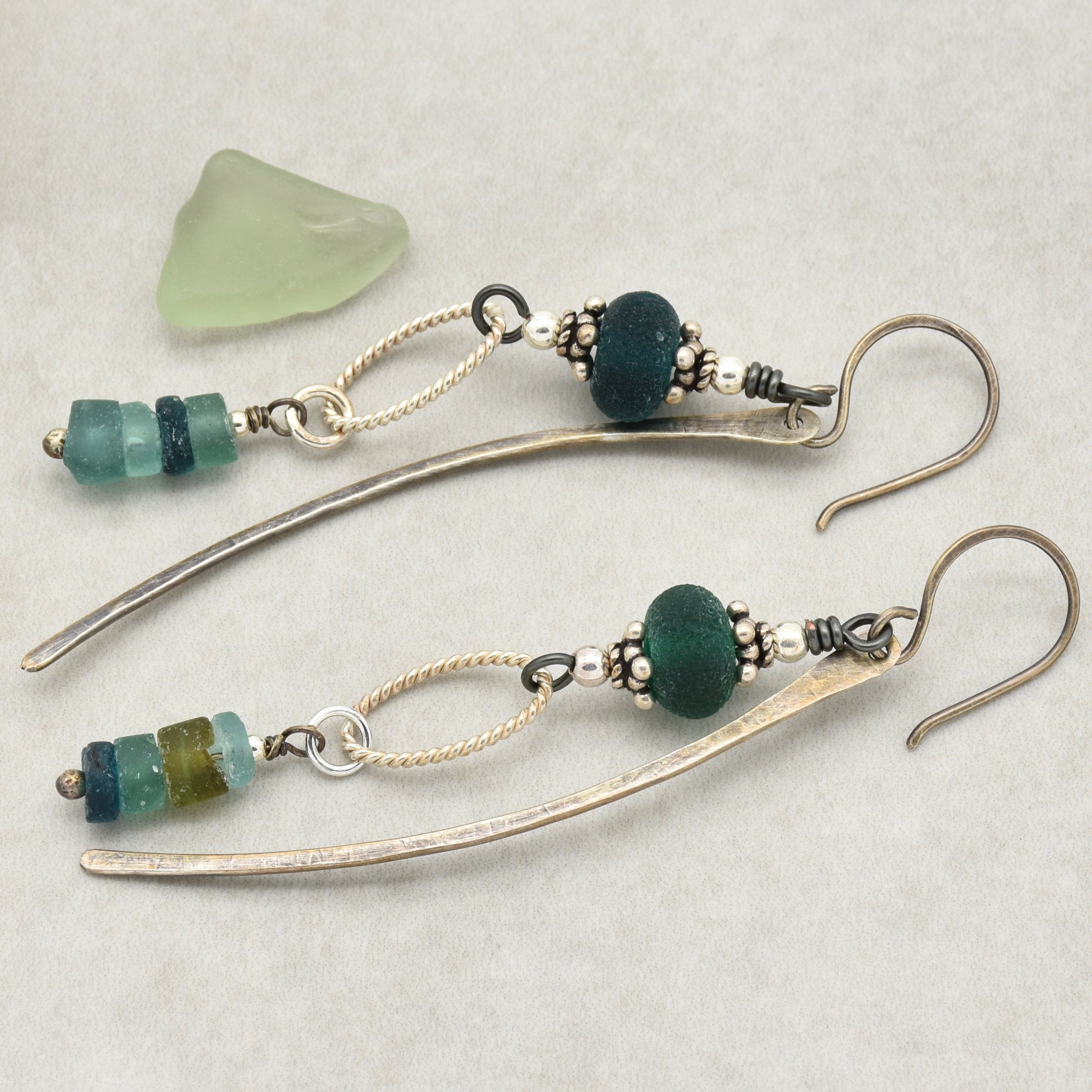 This image shows a pair of earrings. They are long, dangling earrings with a hook for the ear, adorned with beads and metal elements.