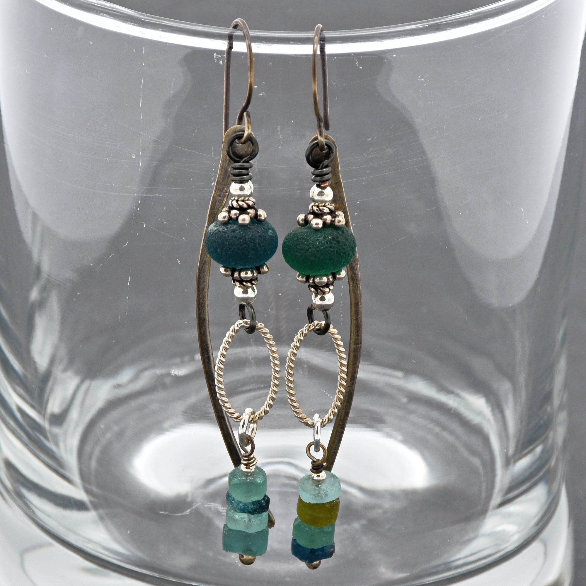 This image shows a pair of earrings. The jewelry pieces have hooks at the top, which are designed to go through pierced earlobes. They feature decorative elements including beads and metal loops.