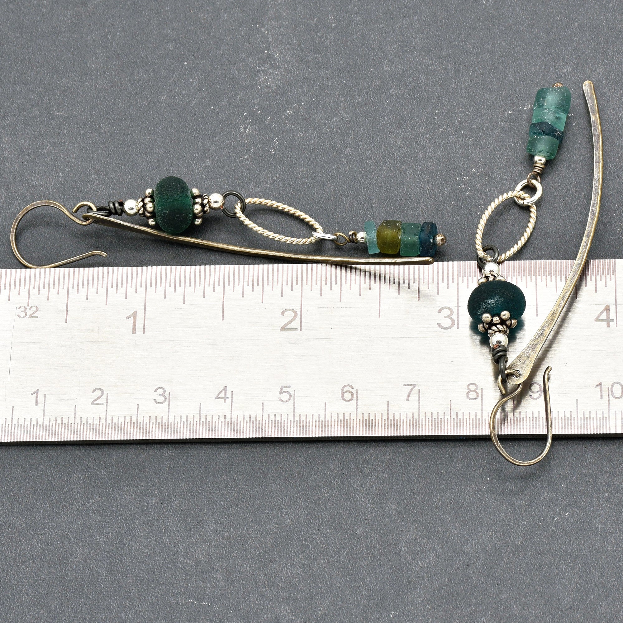 This image shows a pair of earrings. The jewelry pieces have hooks typical of earrings and include decorative beads and loops. The ruler beneath them indicates their length is about 8-9 centimeters.