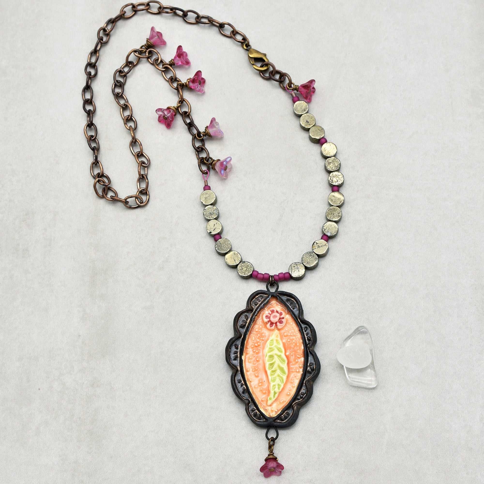 This image shows a necklace. The jewelry piece has a chain with a clasp, decorative beads, and a pendant with a floral design, which are characteristic features of a necklace.