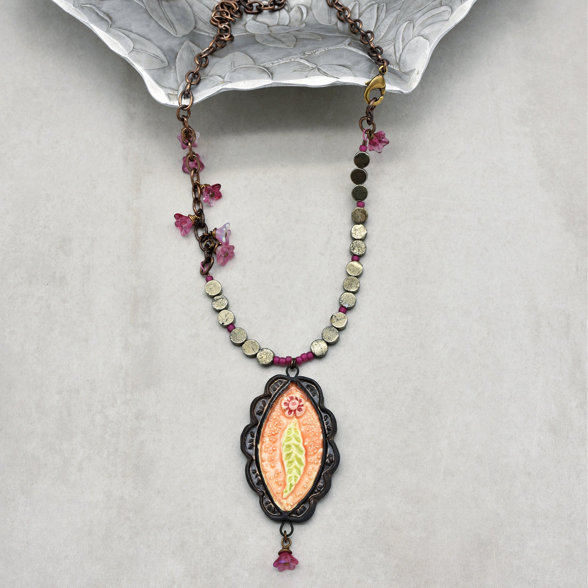 This image shows a necklace. It has a chain with beads and a decorative pendant hanging in the center, typical features of a necklace.