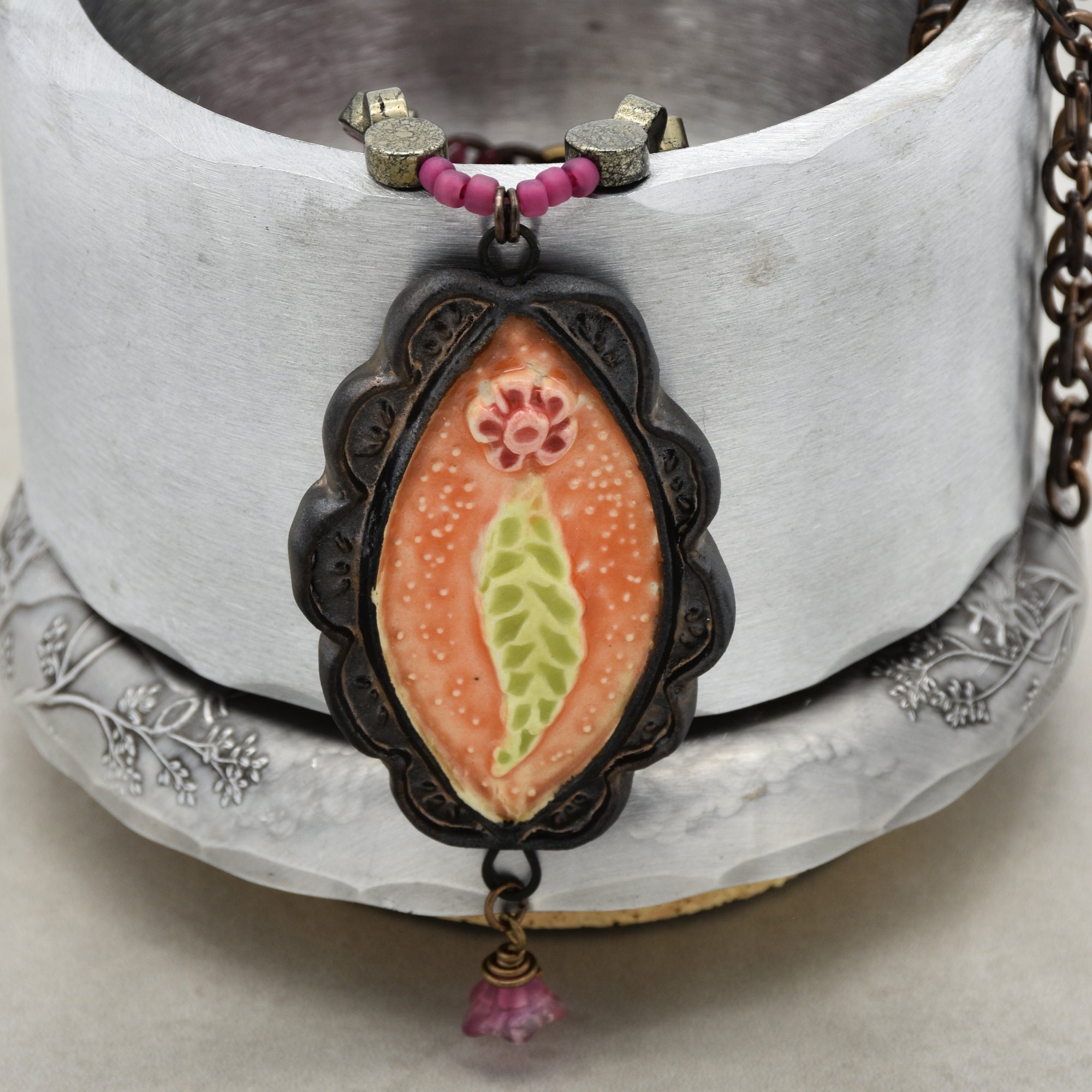 This image shows a necklace. The image features a pendant with beads above it, attached to a chain, which are characteristic elements of a necklace.