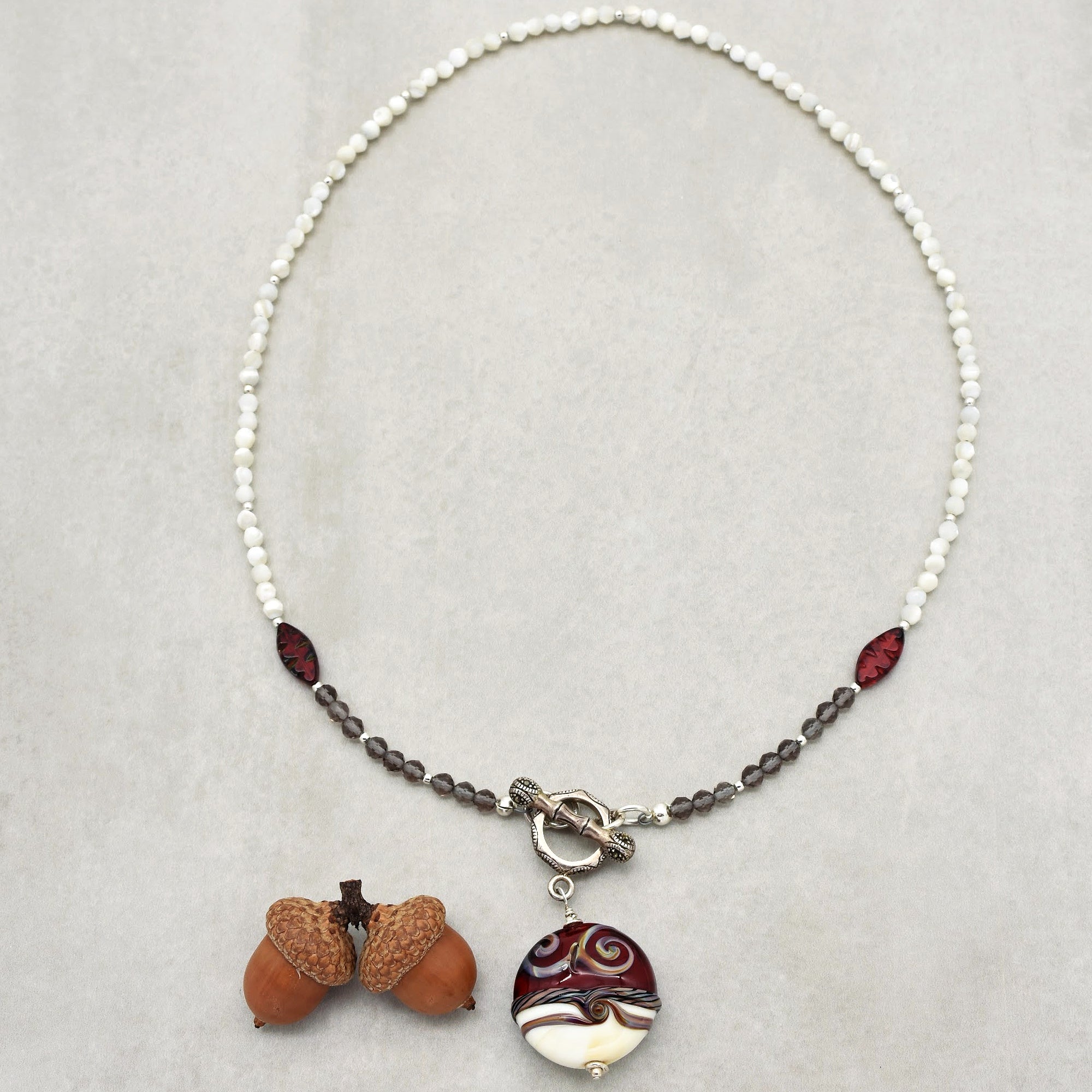 This image shows a necklace. The jewelry piece is designed with small white and dark beads, with a prominent pendant hanging in the center, which suggests it is a necklace rather than an earring or bracelet.