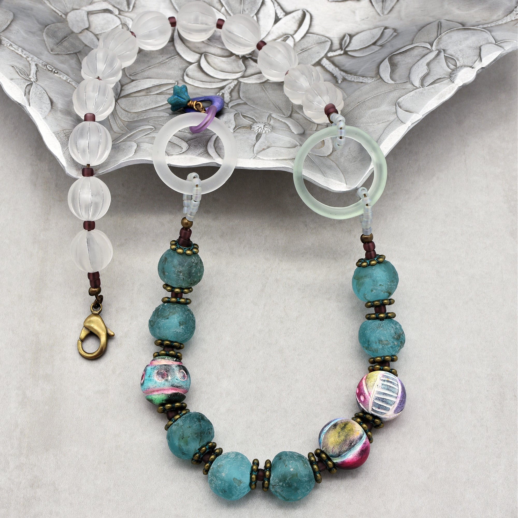 This image shows a necklace. You can identify it as such by the presence of a clasp (at the end on the left side) and the strand of beads designed to go around the neck. The design and length of the jewelry also indicate it is meant to be worn as a necklace.