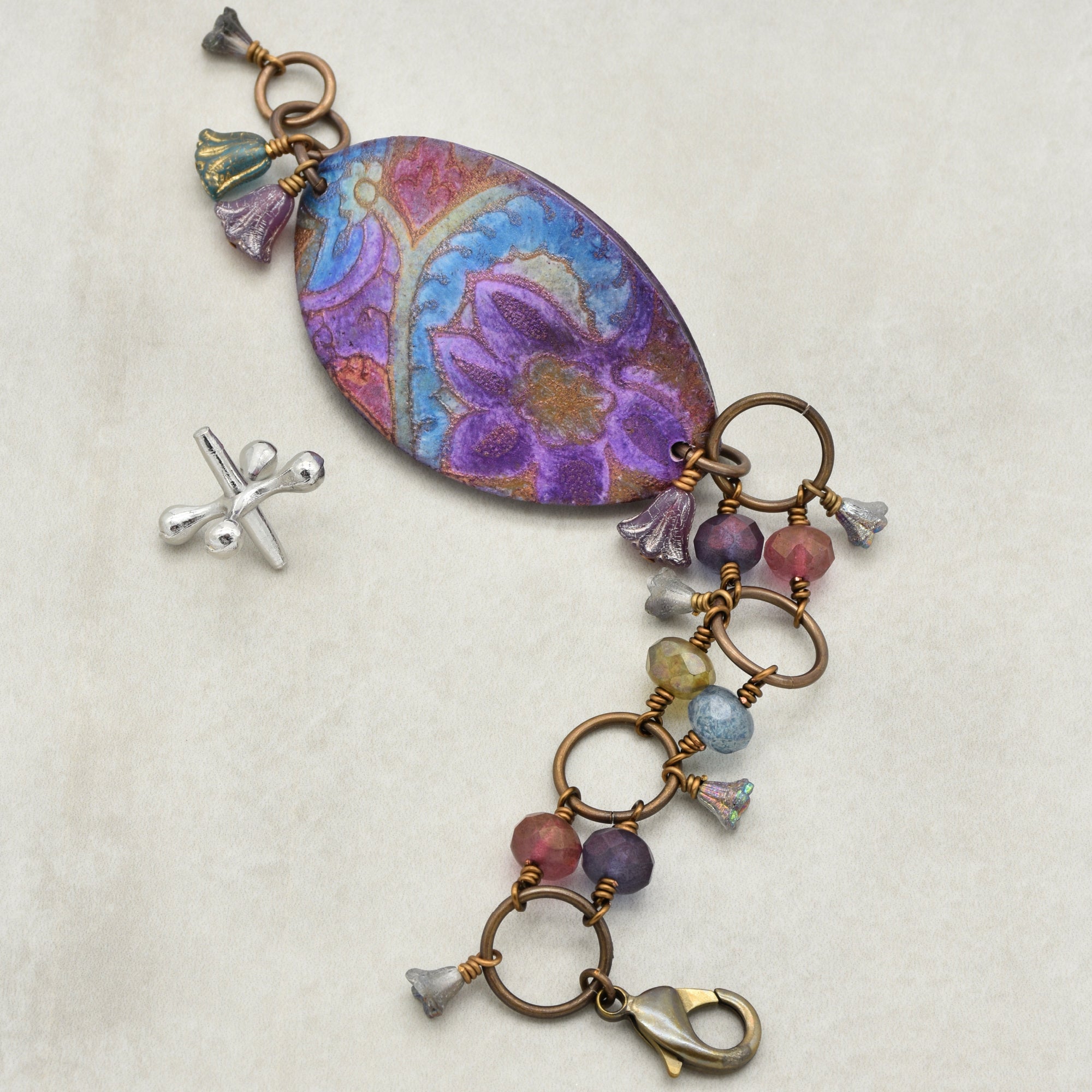 This image shows a piece of jewelry that is a bracelet. The size and the clasp style are indicative of a bracelet rather than a necklace or an earring. The design features colorful beads and floral elements connected by rings, which are typical for bracelets.