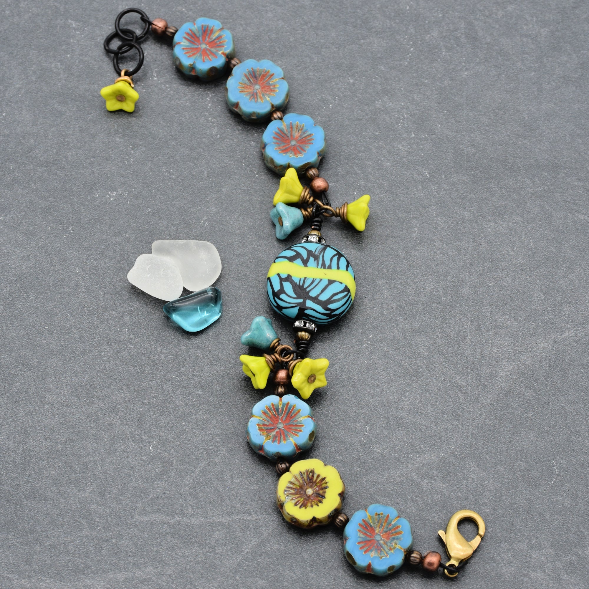 This image shows a bracelet. The size and shape, along with the clasp at the end, indicate that it is designed to be worn around the wrist. The bracelet features colorful flower-shaped beads and other decorative elements.
