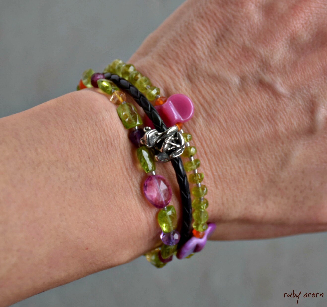 The image shows a bracelet on a wrist. It consists of multiple strands with colorful beads and a small decorative charm.