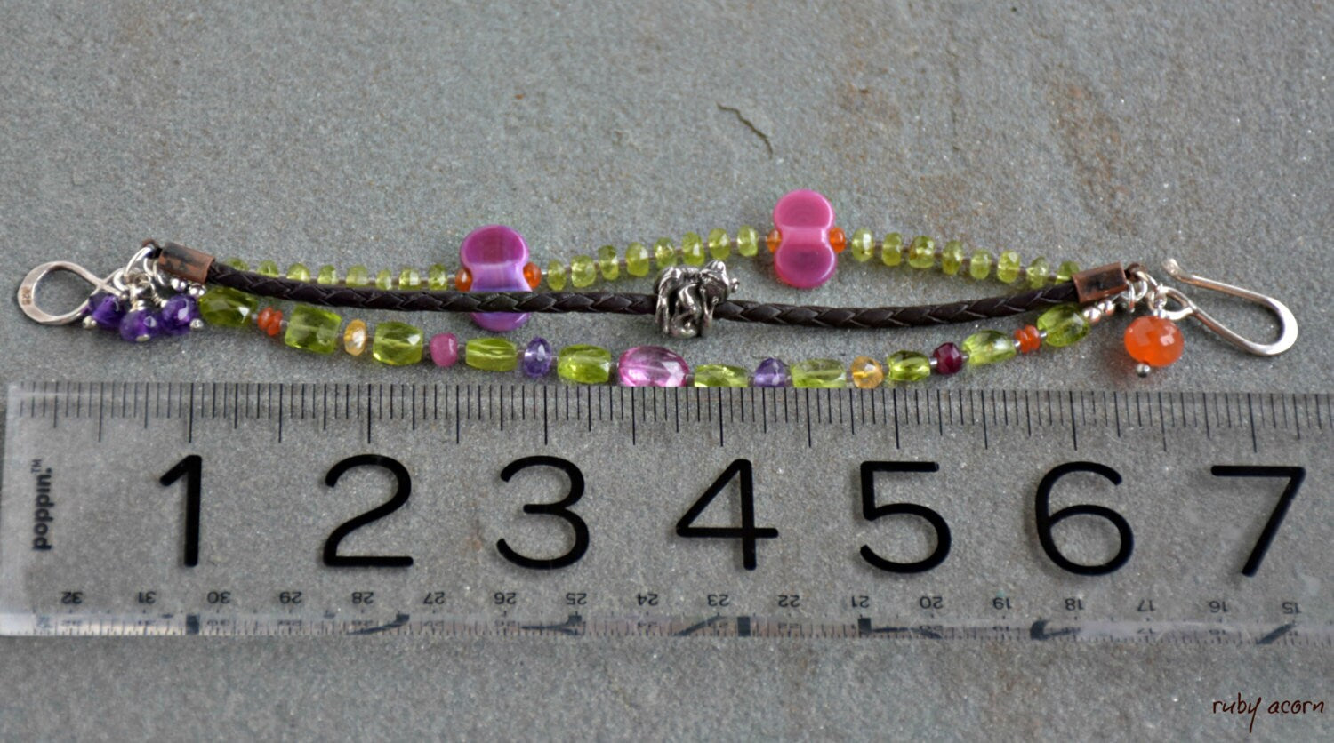 The image shows a bracelet. The length of the jewelry piece, as compared with the ruler below it, suggests it is sized to fit around a wrist. The design, with beads and a clasp, is typical of a bracelet.